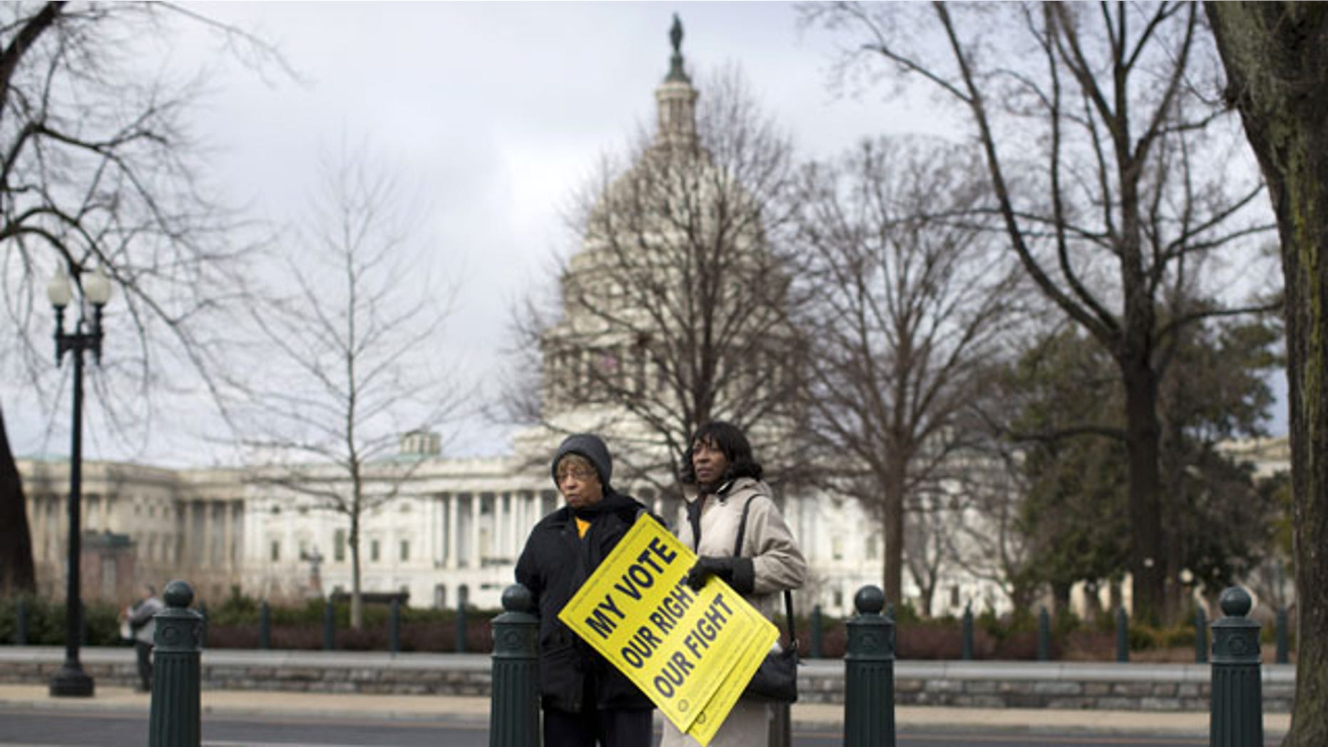 FILE - This Feb. 27, 2013, file photo shows people standing outside the Supreme Court in Washington before the start of a rally during arguments in the Shelby County, Ala., v. Holder case. (AP Photo)