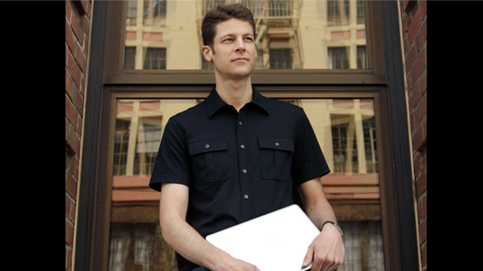 Joshua Kaufman holds up his MacBook laptop outside of his office in San Francisco, Wednesday, June 1, 2011. Kaufman's stolen laptop led police to the suspect by using software that allowed him to track the man's location and take photos of him using the computer.