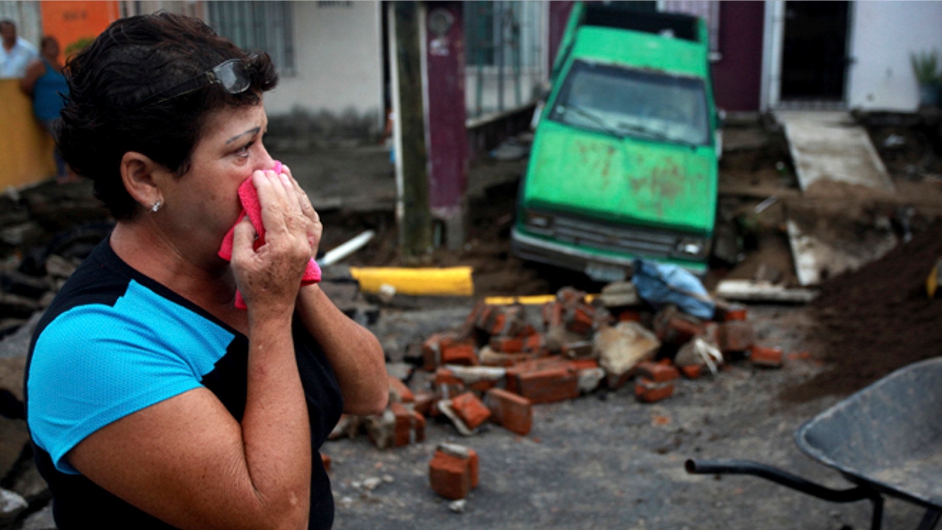Maria del Carmen Gonzalez watches after part of a street and her home collapsed due to heavy rains in the Gulf port city of Veracruz, Mexico, Tuesday Sept. 2, 2014. The Gulf states of Mexico are bracing for more bad weather as Tropical Storm Dolly will cross the coast lat this evening or overnight and continue moving inland over northeastern Mexico on Wednesday. (AP Photo/Felix Marquez)