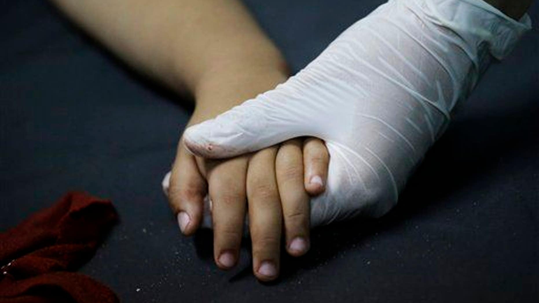A medic, right, holds a young patient's hand in Israel on July 31, 2014.