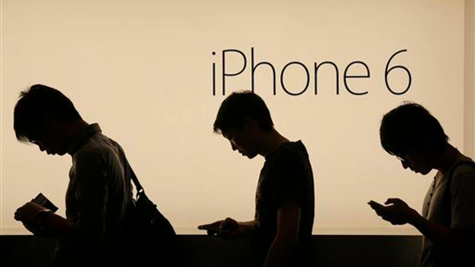 In this photo taken on Friday, Sept. 19, 2014, people wait outside an Apple store in Hong Kong.