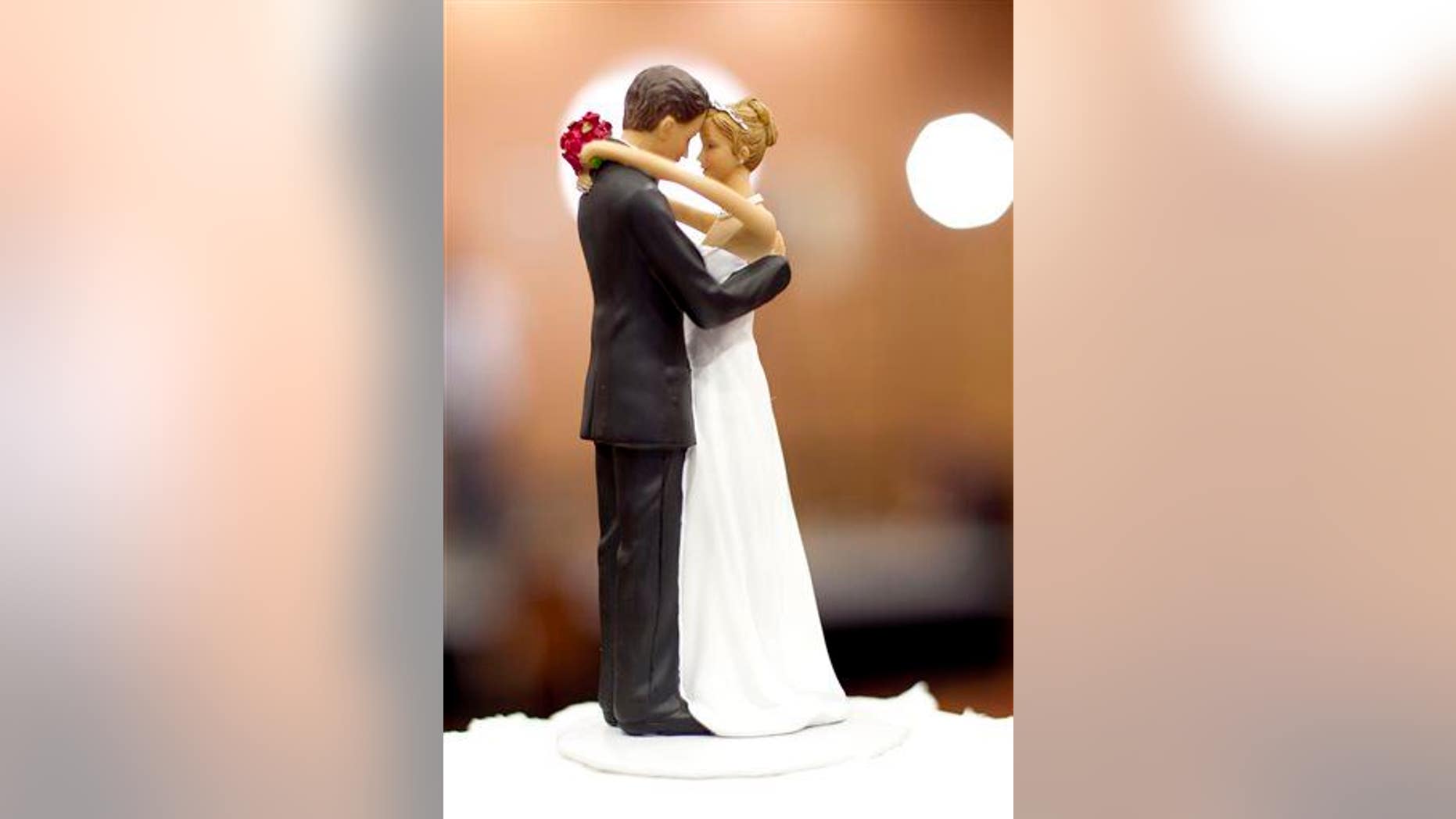Figurines of a bride and a groom sit atop a wedding cake in Raleigh, N.C., on Tuesday May 8, 2012.