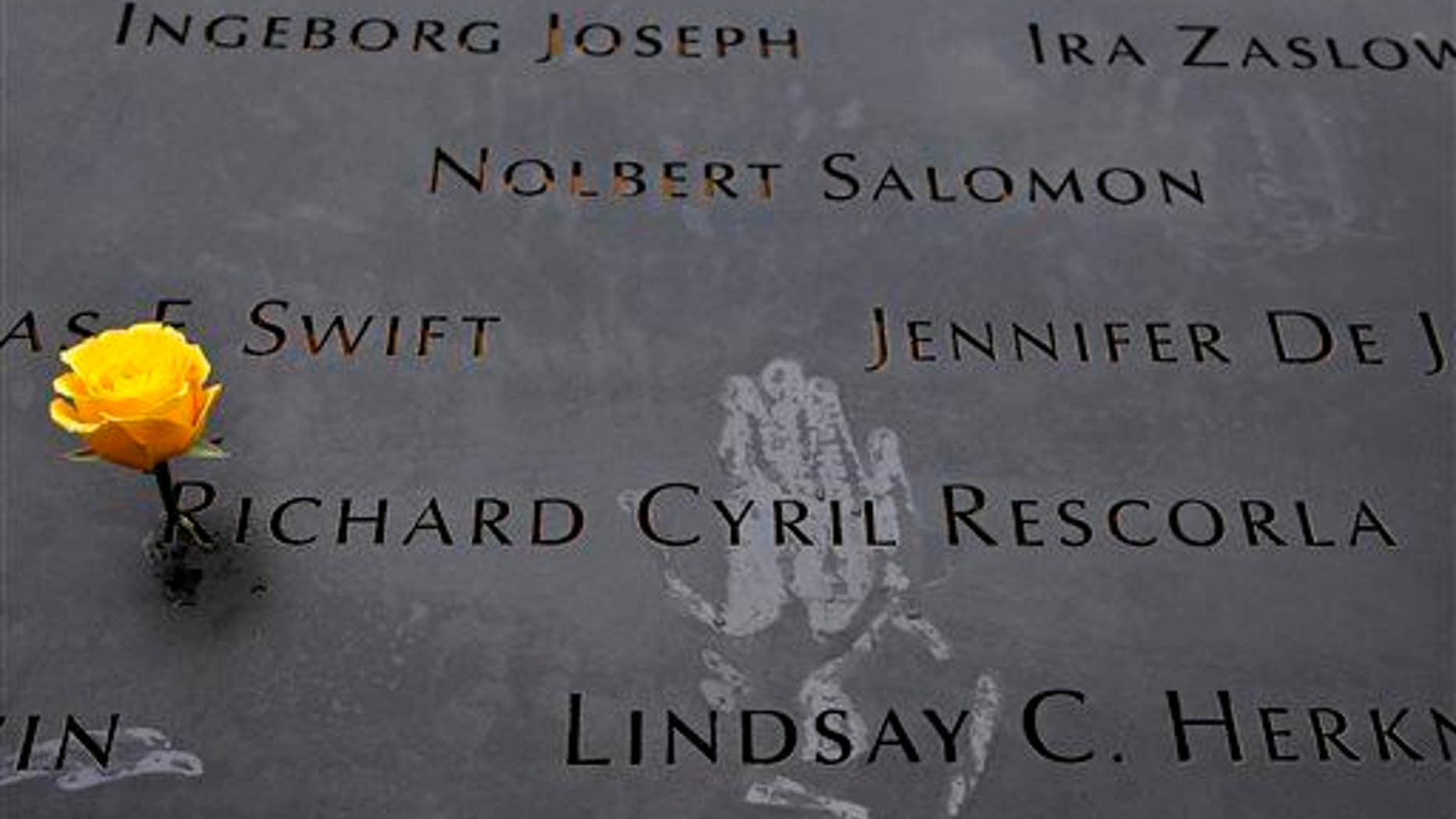 A yellow rose stands wedged into a name at the South Pool of the National September 11 Memorial in New York.