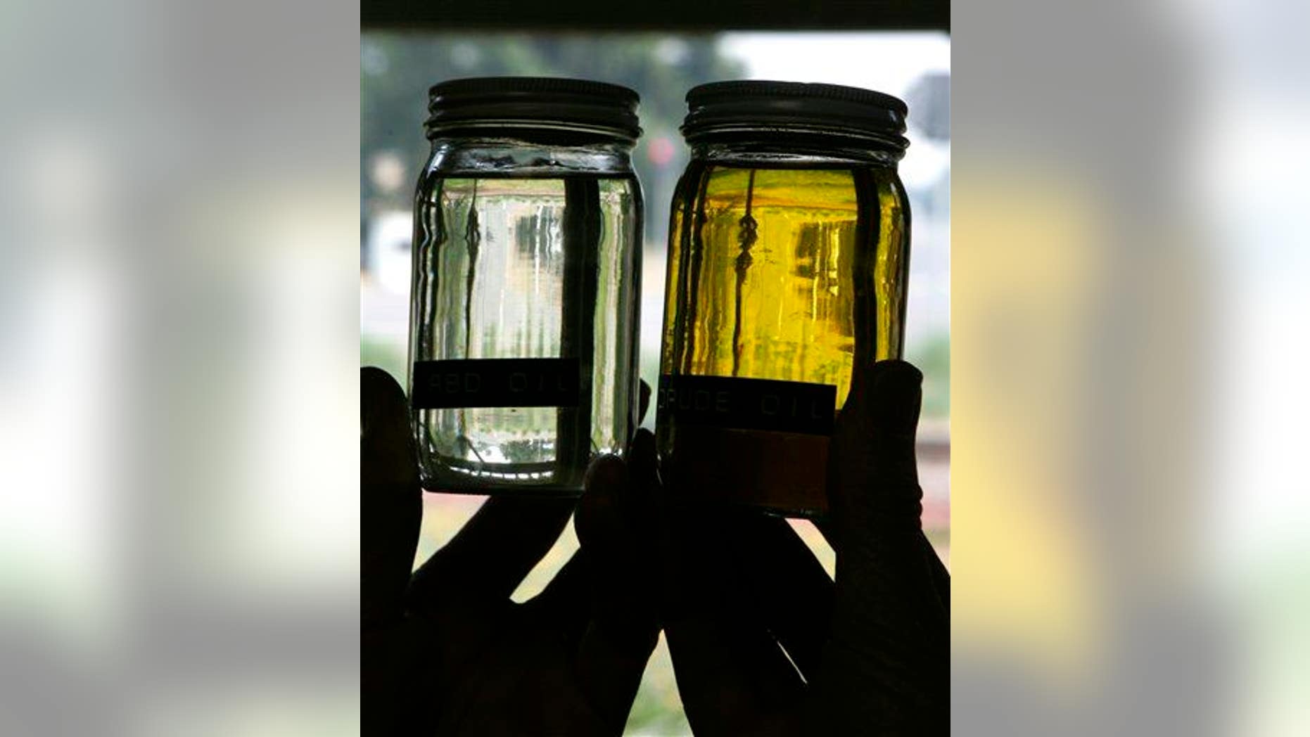 Jars of clear, processed safflower oil, left, and unprocessed oil, right are displayed.