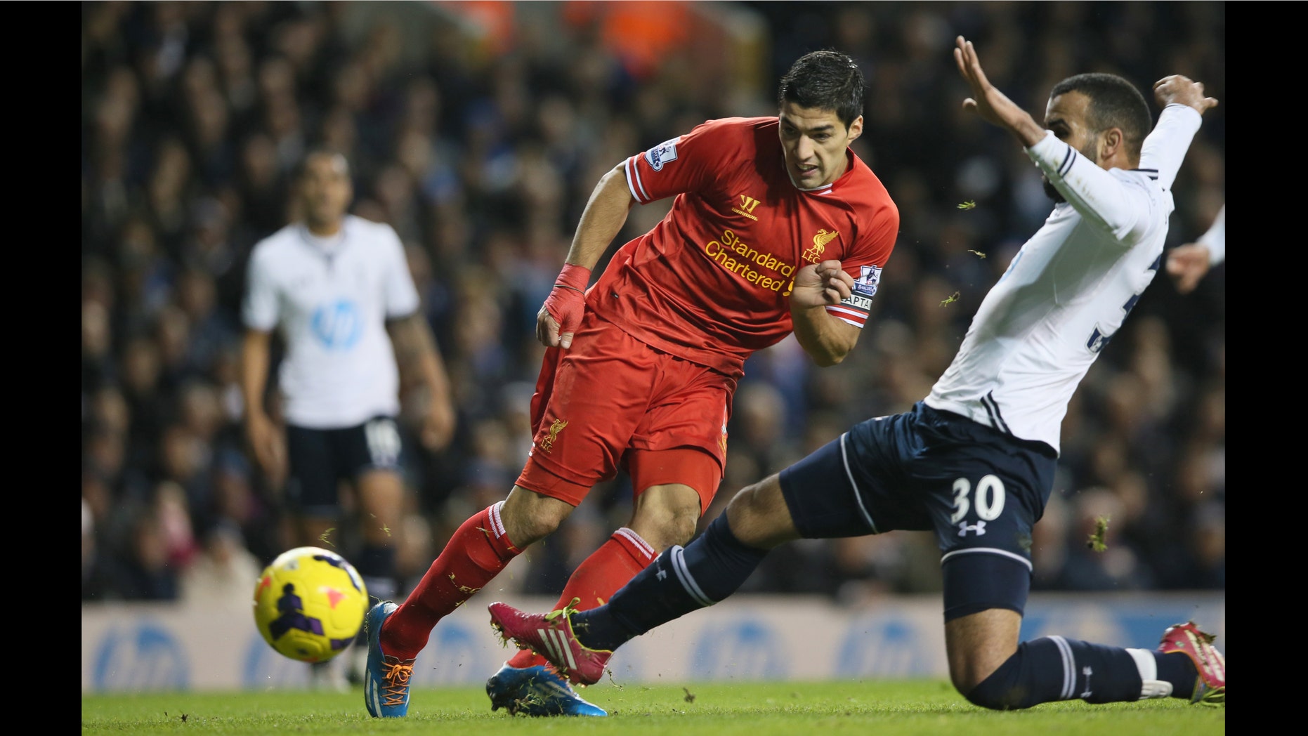 Liverpool's Luis Suarez, left, shoots and scores the opening goal during their English Premier League soccer match between Tottenham Hotspur and Liverpool at the White Hart Lane stadium in London Sunday, Dec. 15, 2013. (AP Photo/Alastair Grant)