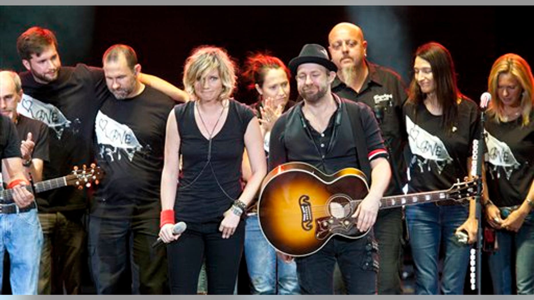 August 18: Surrounded by their tour crew, Sugarland duo Jennifer Nettles and Kristian Bush react after performing in Albuquerque, N.M. during a tribute for the victims of a stage collapse at the Indiana State Fair that killed six people.