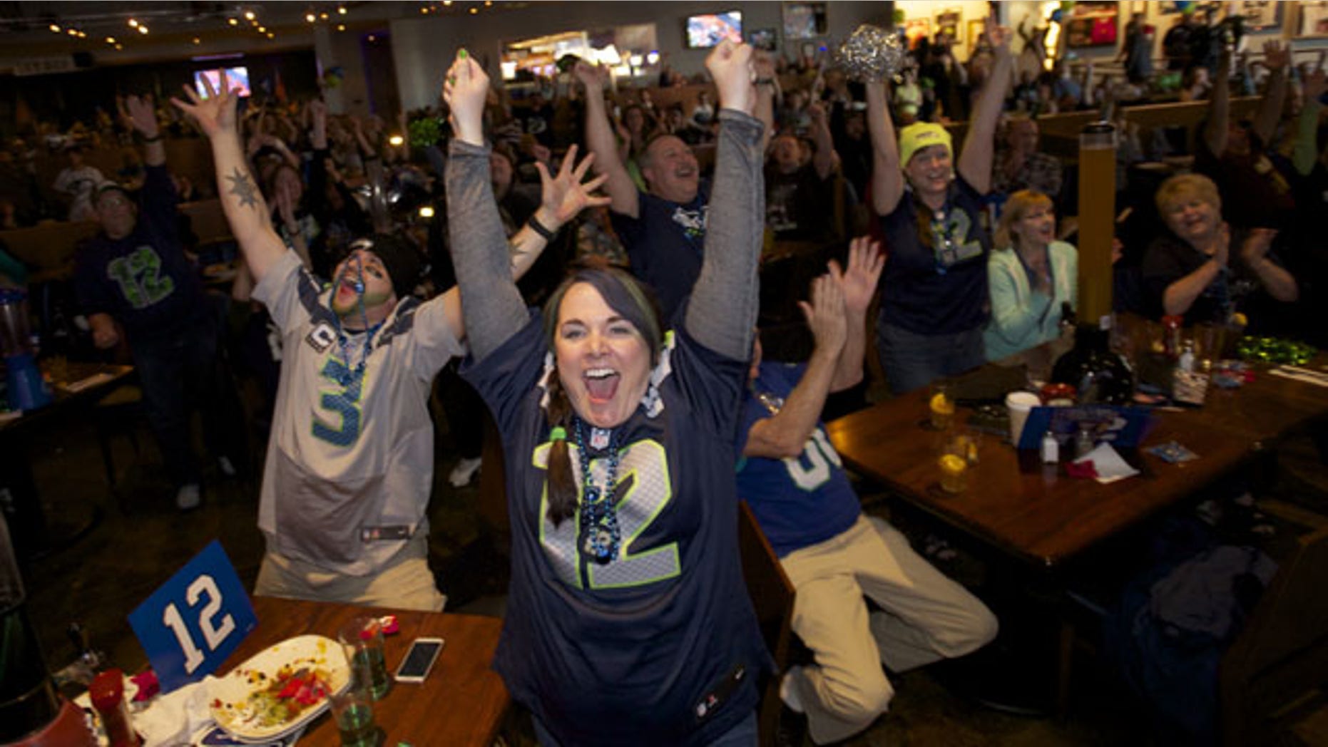 February 2, 2014: Seattle Seahawks fans Brittney Gutierrez, center, and her husband Mike Gutierrez, left, celebrate while watching Super Bowl XLVIII at Big Al's in Vancouver, Wash. Seattle defeated the Denver Broncos 43-8. (AP Photo/The Columbian, Steven Lane)