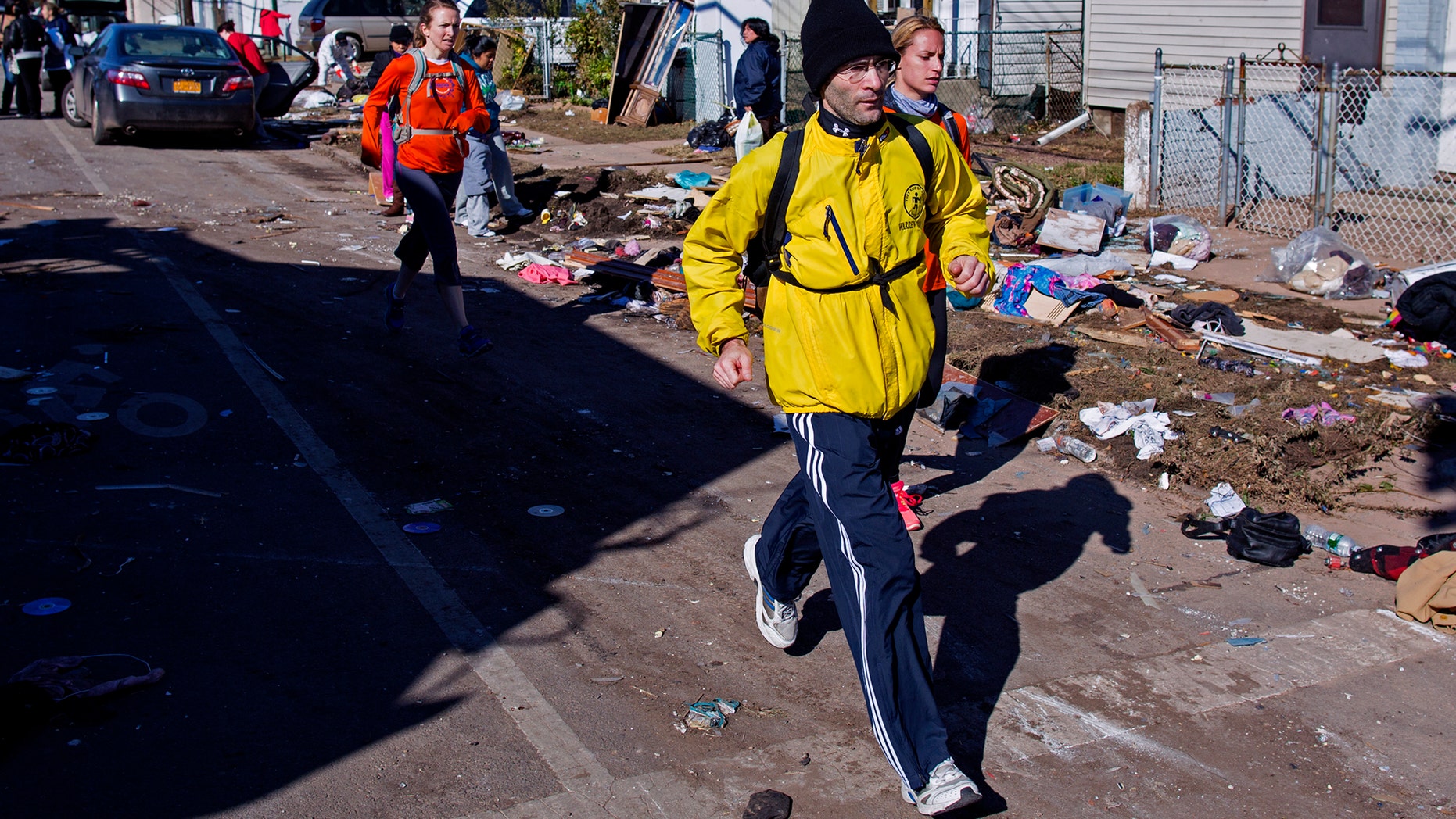 Nov. 4, 2012: Carrying a backpack with goods and supplies, marathon runner Eitan Tabak runs past debris in the hard hit Midland Beach neighborhood of the Staten Island borough of New York. Background right is marathon runner Michelle Mascioli and far left marathon runner Rachel Wheeler of New York.