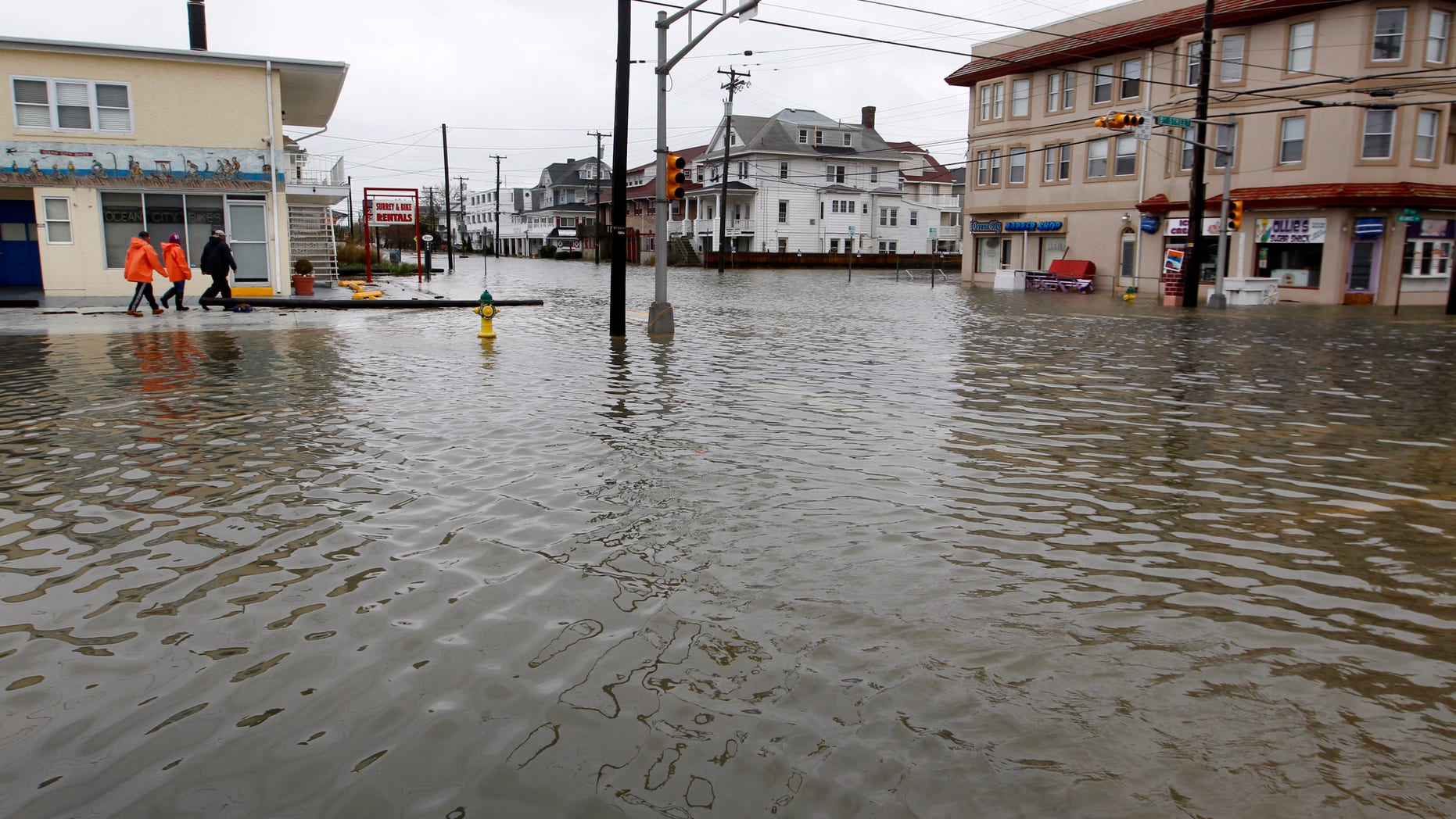 People walk along a flooded intersection of 8th Street and Atlantic Avenue, in Ocean City, N.J., Tuesday, Oct. 30, 2012, after the storm surge from Sandy flooded much of the town. Sandy, the storm that made landfall Monday, caused multiple fatalities, halted mass transit and cut power to more than 6 million homes and businesses. (AP Photo/Mel Evans)