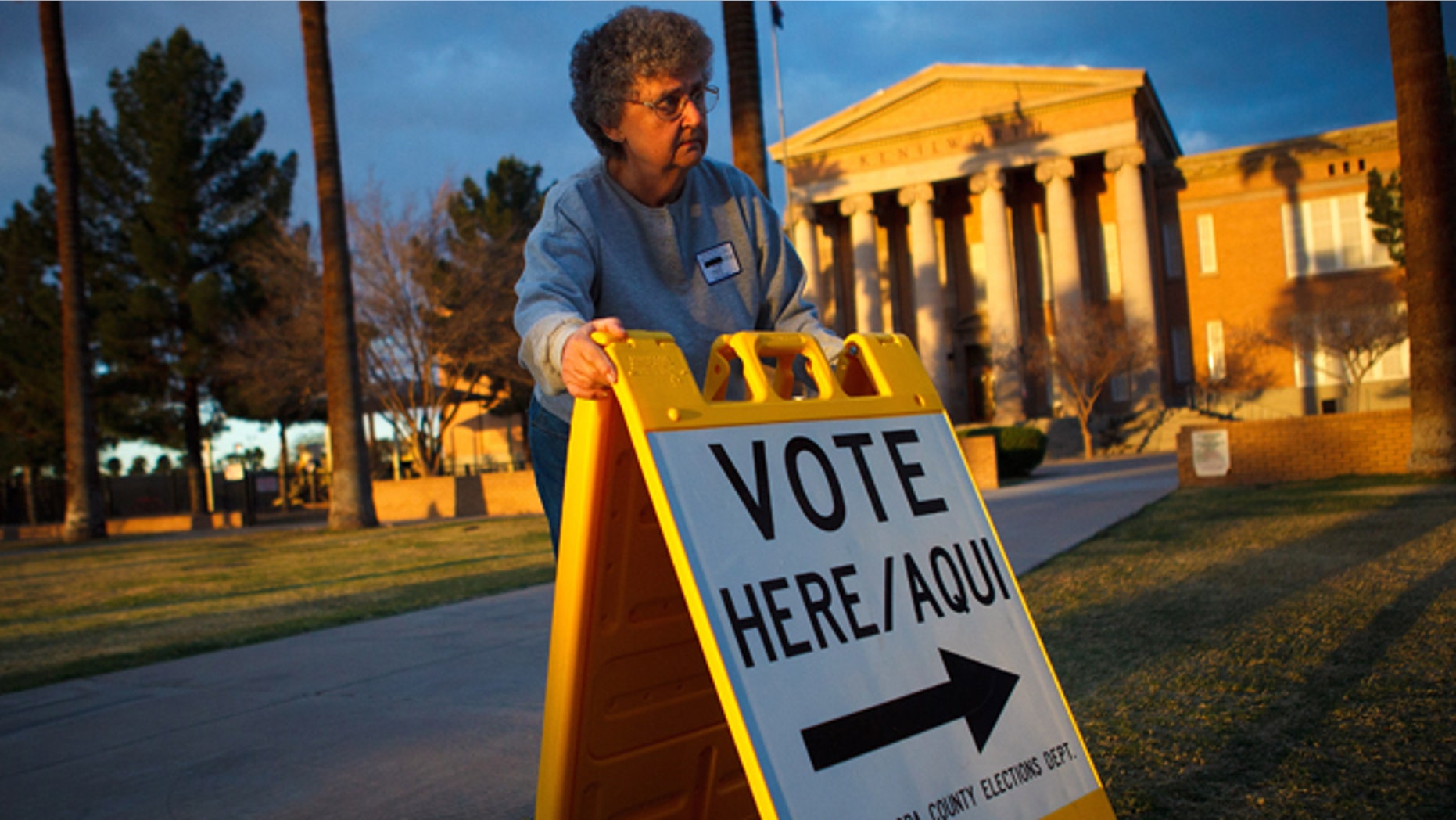 PHOENIX, AZ - FEBRUARY 28: Election day volunteer Vicki Groff places a sign to direct voters to a polling station at Kenilworth School February 28, 2012 in Phoenix, Arizona. Voters in this state participate in choosing who will be the Republican candidate to contest President Barack Obama in the general election. (Photo by Jonathan Gibby/Getty Images)