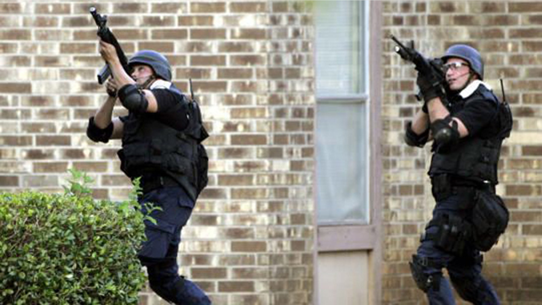 Members of a SWAT unit take aim at a second floor apartment window during a 2006 standoff in which a shooter wounded three police officers and a state trooper.