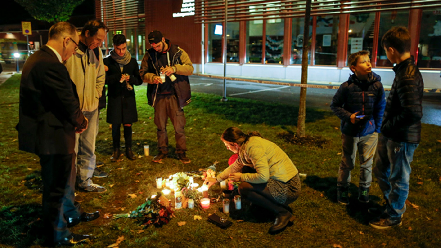 Oct. 22, 2015: People light candles and lay flower tributes outside the school where a masked man stabbed four people in Trollhattan, Sweden. The man killed one teacher and a student before being shot by police, authorities said. (Adam Ihse/TT via AP)