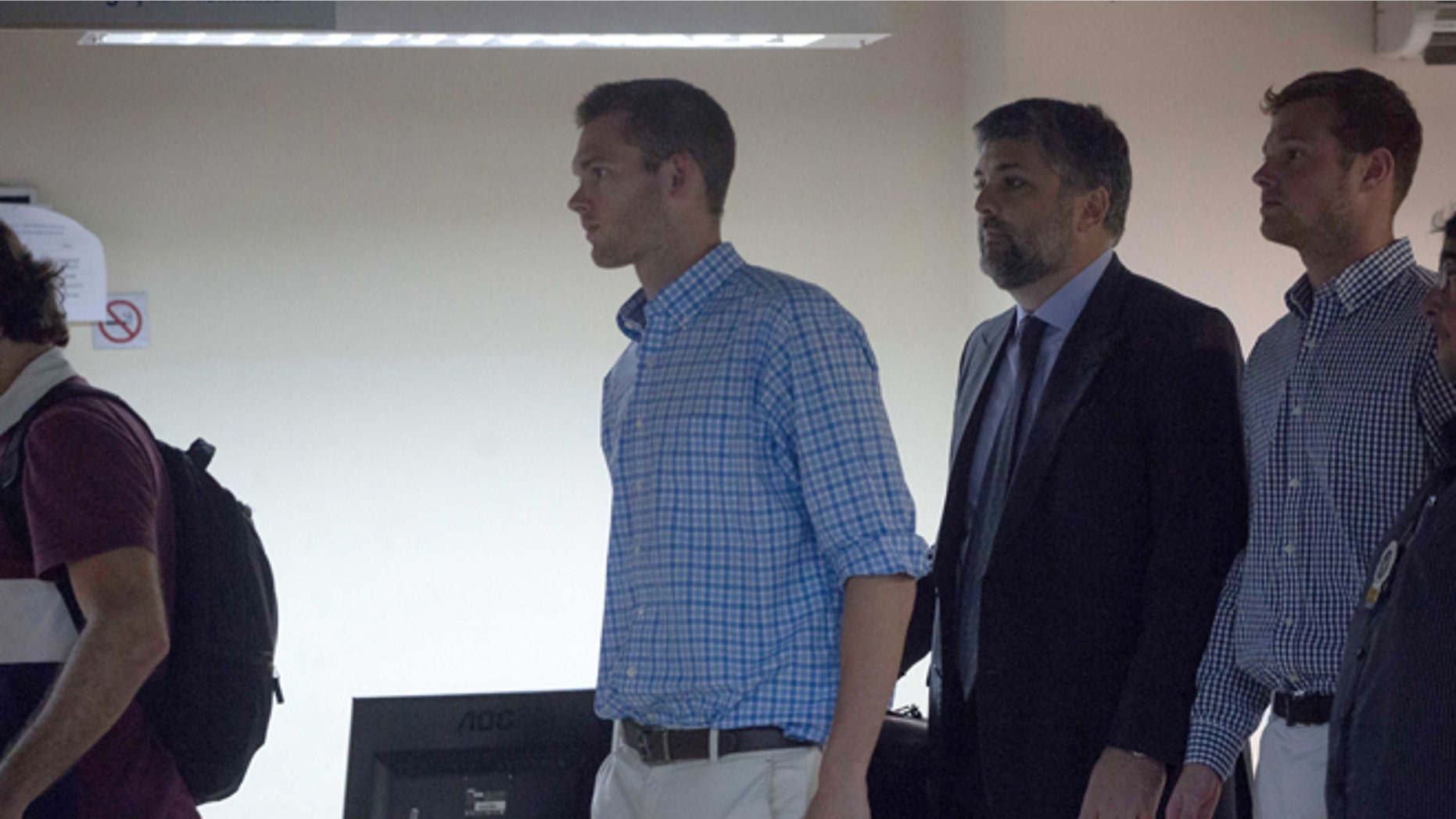 Accompanied by Brazilian lawyer Sergio Riera, second from right, American Olympic swimmers Gunnar Bentz, left, and Jack Conger, right, leave a police station in the Leblon neighborhood of Rio de Janeiro, Brazil, Thursday, Aug. 18, 2016. The two were taken off their flight from Brazil to the U.S. on Wednesday by local authorities amid an investigation into a reported robbery targeting Ryan Lochte and his teammates. A Brazilian police officer told The Associated Press that Lochte fabricated a story about being robbed at gunpoint in Rio de Janeiro. (AP Photo/Mauro Pimentel)