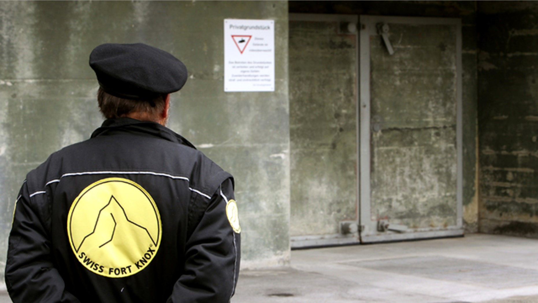 A security guard stands in front of a gate of the Swiss Fort Knox bunker in the mountains near the Swiss Alpine resort of Saanen May 18, 2010. In the secret bunker, European researchers deposited a "digital genome" that will provide the blueprint for future generations to read data stored using defunct technology.