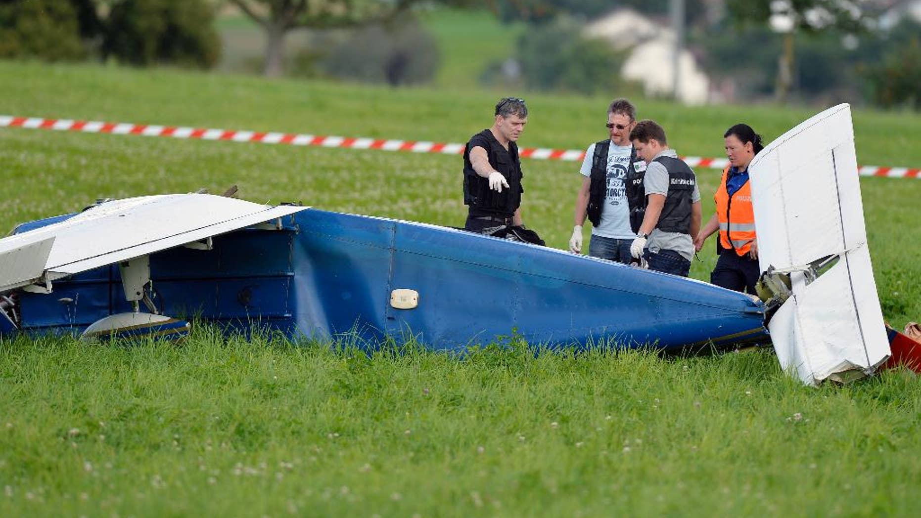 Police inspect the wreckage of a small plane that collided with another plane and crashed during an emergency landing near Moerikon, Switzerland, Sunday Aug. 24, 2014. Police say two small planes have collided over northeastern Switzerland, injuring seven people.St. Gallen canton (state) police said the aircraft both made emergency landings after Sunday’s collision- one in a field and the other at an airfield. The pilot and three passengers aboard the plane that landed in the field were seriously injured. The pilot of the other plane and its two passengers also were injured.There was no word on the cause of the collision. (AP Photo/Keystone, Walter Bieri)