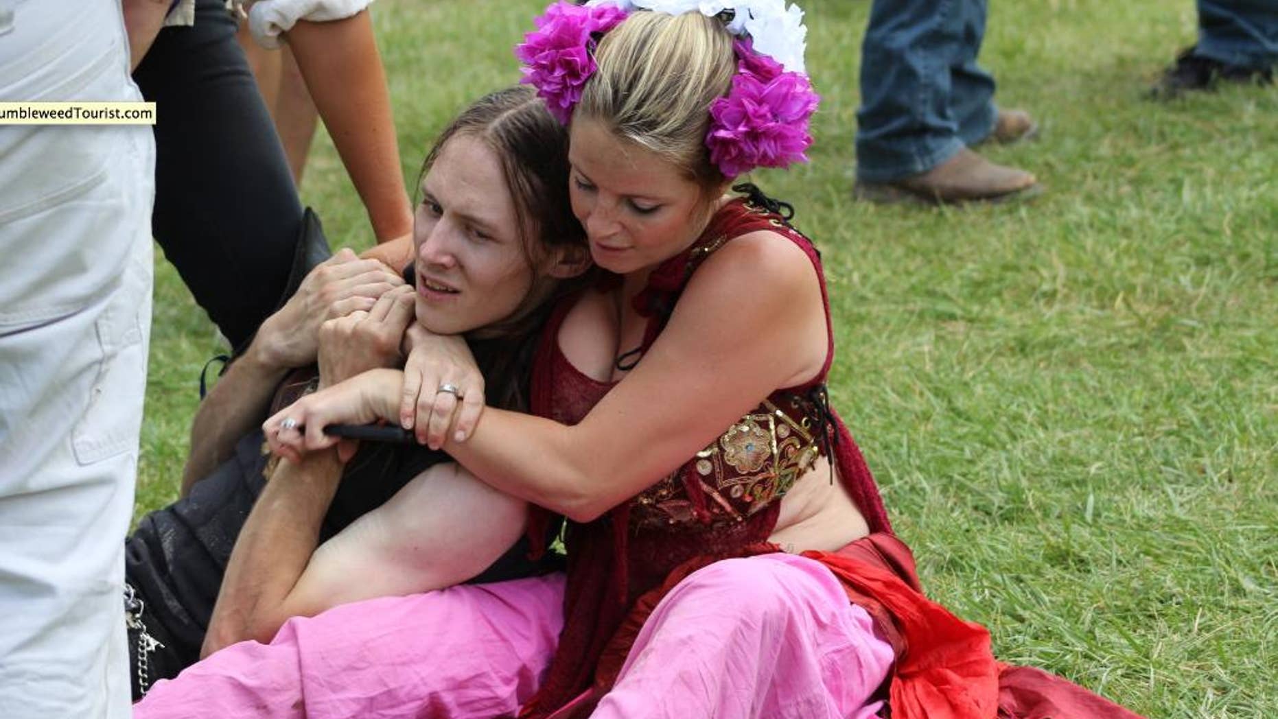In this Saturday, July 11, 2015 photo, provided by Steven Chapman, a renaissance festival attendee, right, restrains 22-year-old man Connor Ward, after he allegedly made off with a sword at the Colorado Renaissance Festival, in Larkspur, Colo. Ward is facing charges of theft and resisting arrest after authorities say he crashed a jousting performance at the Colorado Renaissance Festival and tried to take a sword. A witness said the man was chased down by two women in costume. (Steven Chapman/TumbleweedTourist.com via AP) MANDATORY CREDIT