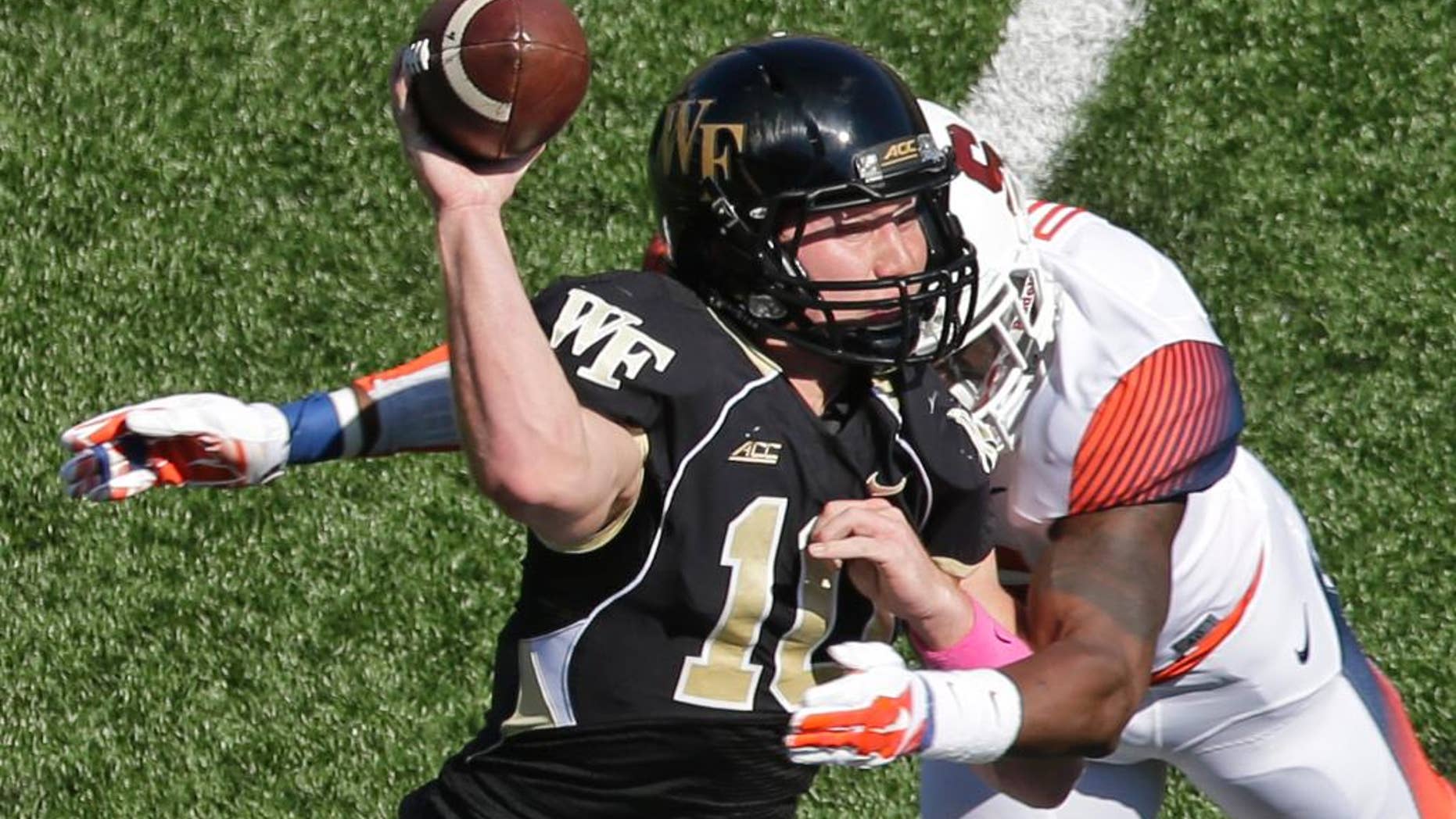 Wake Forest's John Wolford, left, is hit by Syracuse's Dyshawn Davis, right, during the first half of an NCAA college football game in Winston-Salem, N.C., Saturday, Oct. 18, 2014. Wolford left the game after the play. (AP Photo/Chuck Burton)
