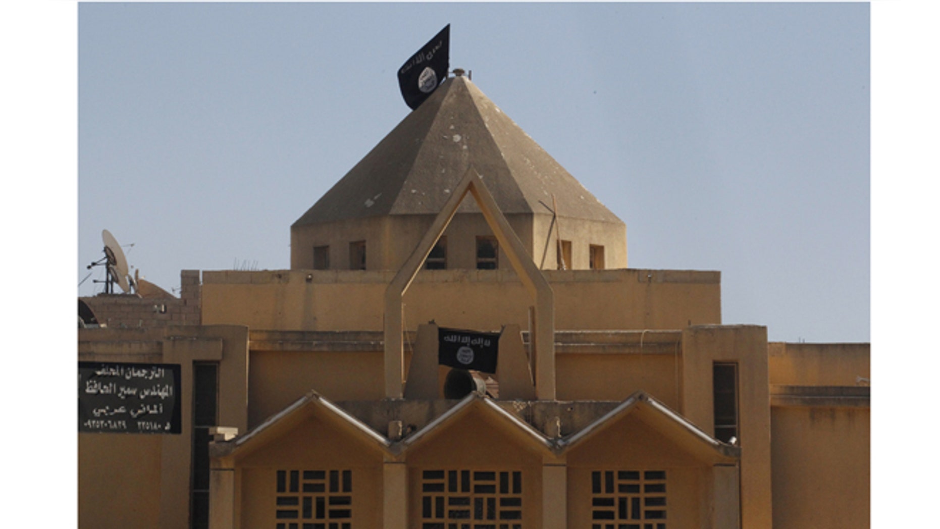 September 27, 2013: Flags of the Islamic State of Iraq and the Levant are hung on The Martyrs Church in the city of Raqqa. The Al-Qaeda linked groups removed crosses from the structure and hoisted their flags.