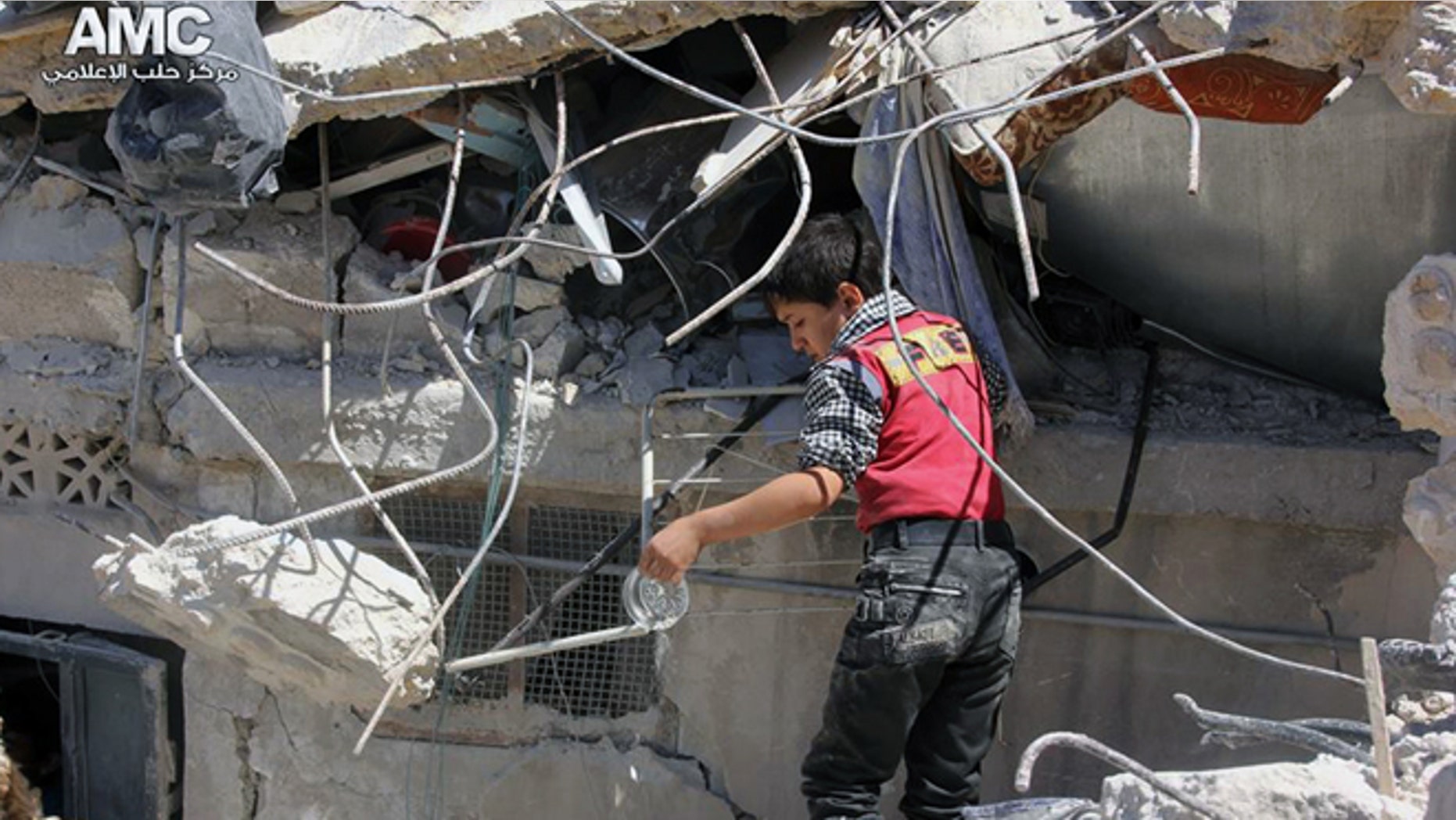May 18, 2014: This photo provided by the anti-government activist group Aleppo Media Center (AMC), which has been authenticated based on its contents and other AP reporting, shows a Syrian young inspecting the rubble of houses that were destroyed by airstrikes from the Syrian government forces in Aleppo, Syria. (AP/Aleppo Media Center, AMC)