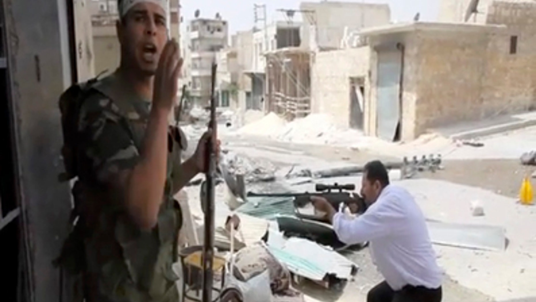Sept. 1, 2012: In this image made from video and accessed a Free Syrian Army fighter calls out to comrades as another fighter fires at Syrian Army positions in Aleppo, Syria.