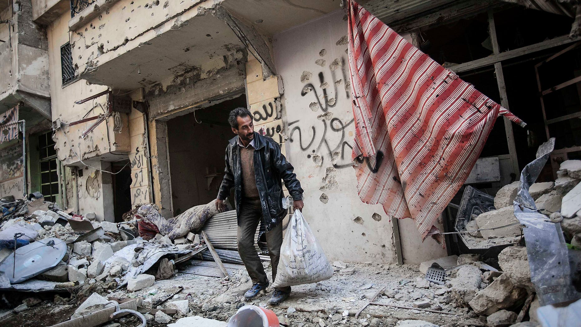 Dec. 2, 2012: In this photo, a man collects his belongings after his home was damaged due to heavy fighting between Free Syrian Army fighters and government forces in Aleppo, Syria.