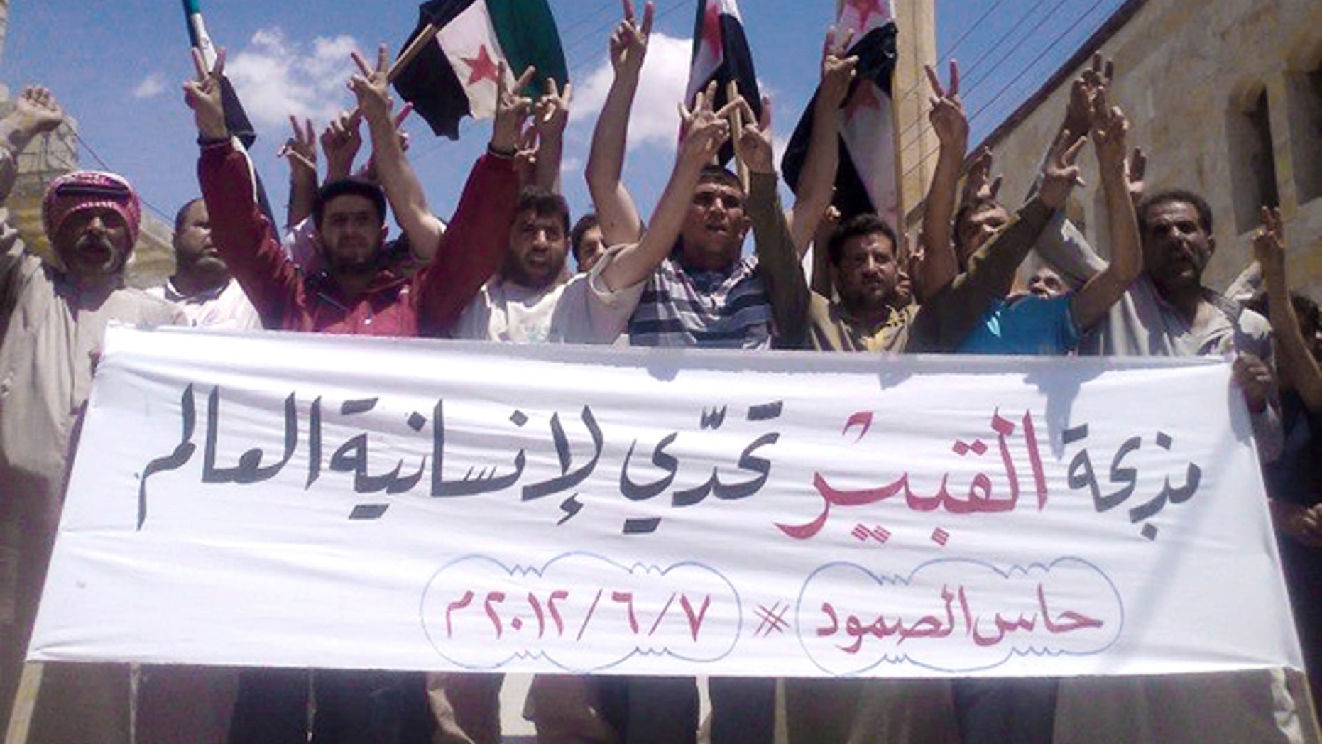 June 7, 2012: In this citizen journalism image provided by Edlib News Network ENN, anti-Syrian regime protesters chant slogans and hold a banner in Arabic that reads, "Al-Qubair massacre challenges the world's humanity,"during a protest against the massacre of Mazraat al-Qubair, in the northern village of Hass, in Idlib province, Syria.