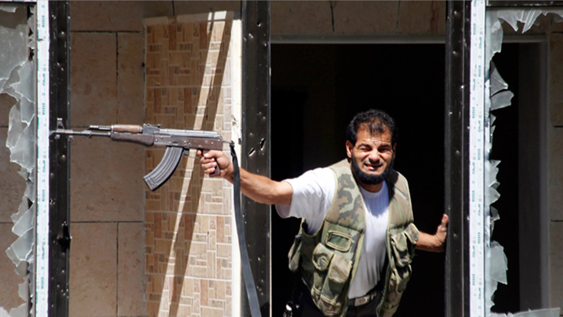 FILE: Sept. 13, 2013: A Free Syrian Army fighter fires his weapon at the Justice Palace, controlled by President Bashar al-Assad, in Aleppo, Syria.