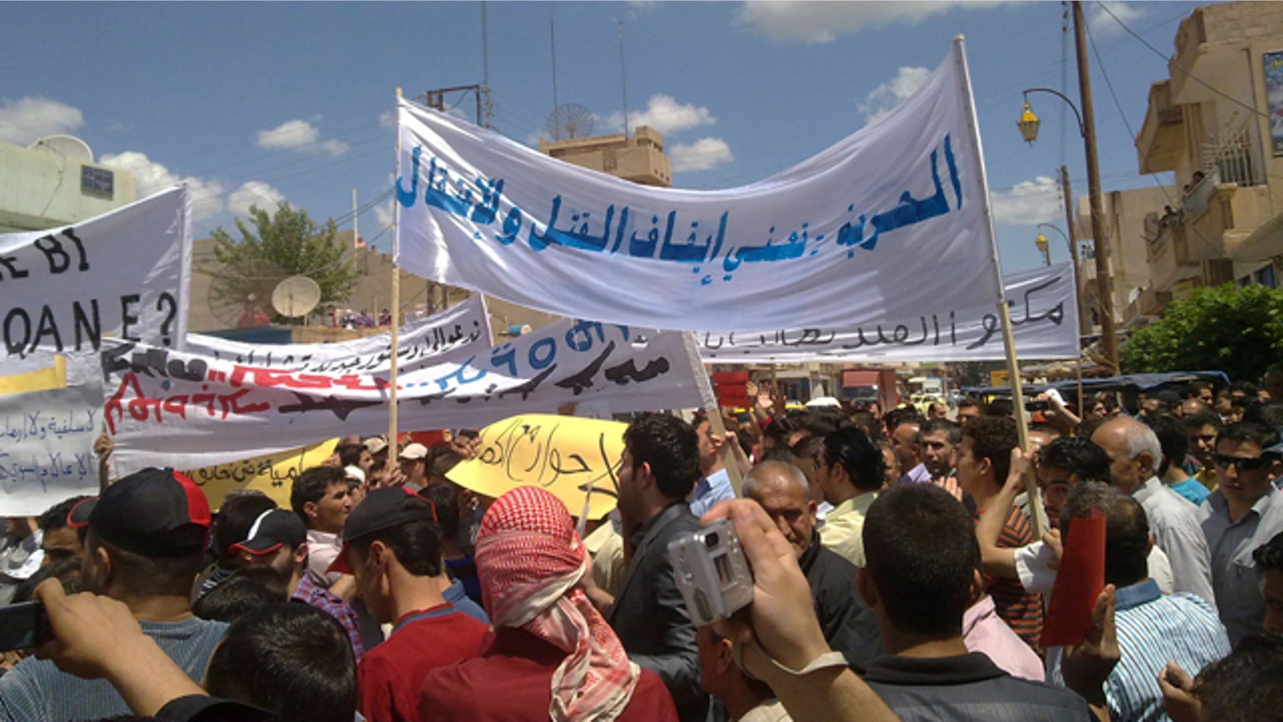 May 13: In this citizen journalism image made on a mobile phone and acquired by the AP, Syrian anti-government protesters carry banners in Arabic that read: "Freedom means to stop the killing and arrests," during a rally in the northeastern city of Qamishli, Syria.