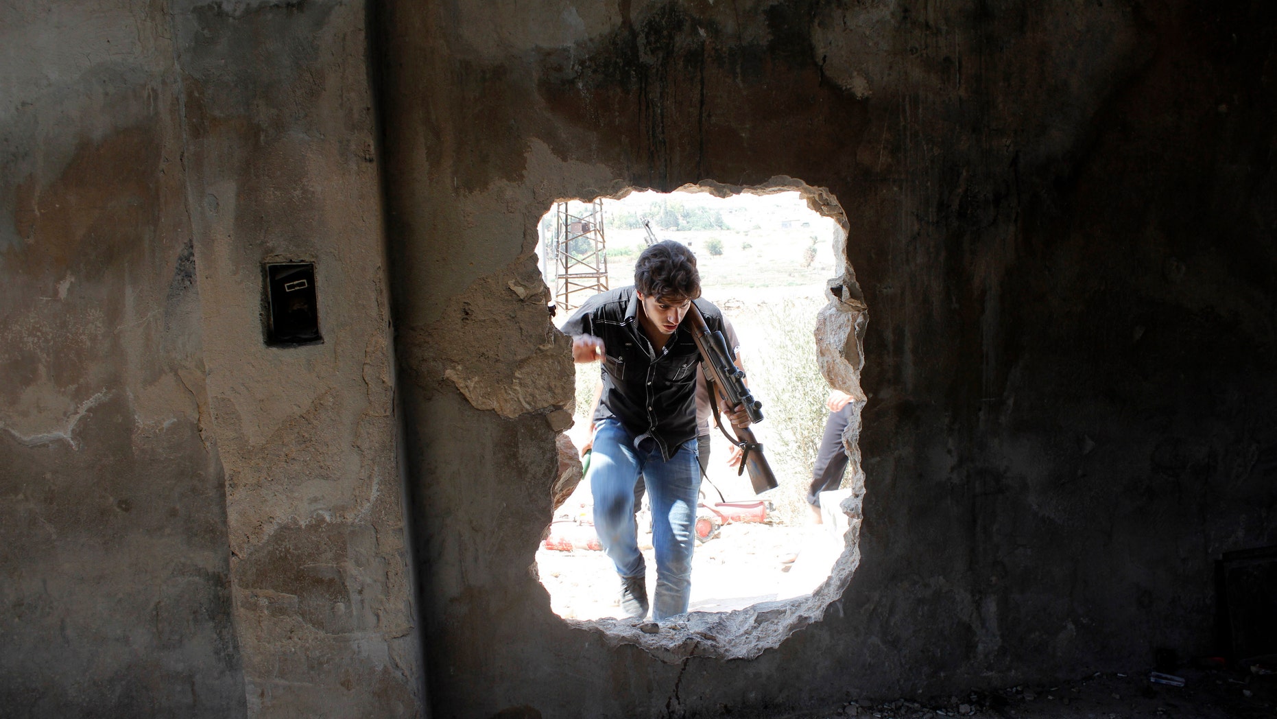 A Free Syrian Army fighter walks through a hole in a wall beside the Canadian Hospital in Aleppo, August 31, 2013. (REUTERS/Molhem Barakat)