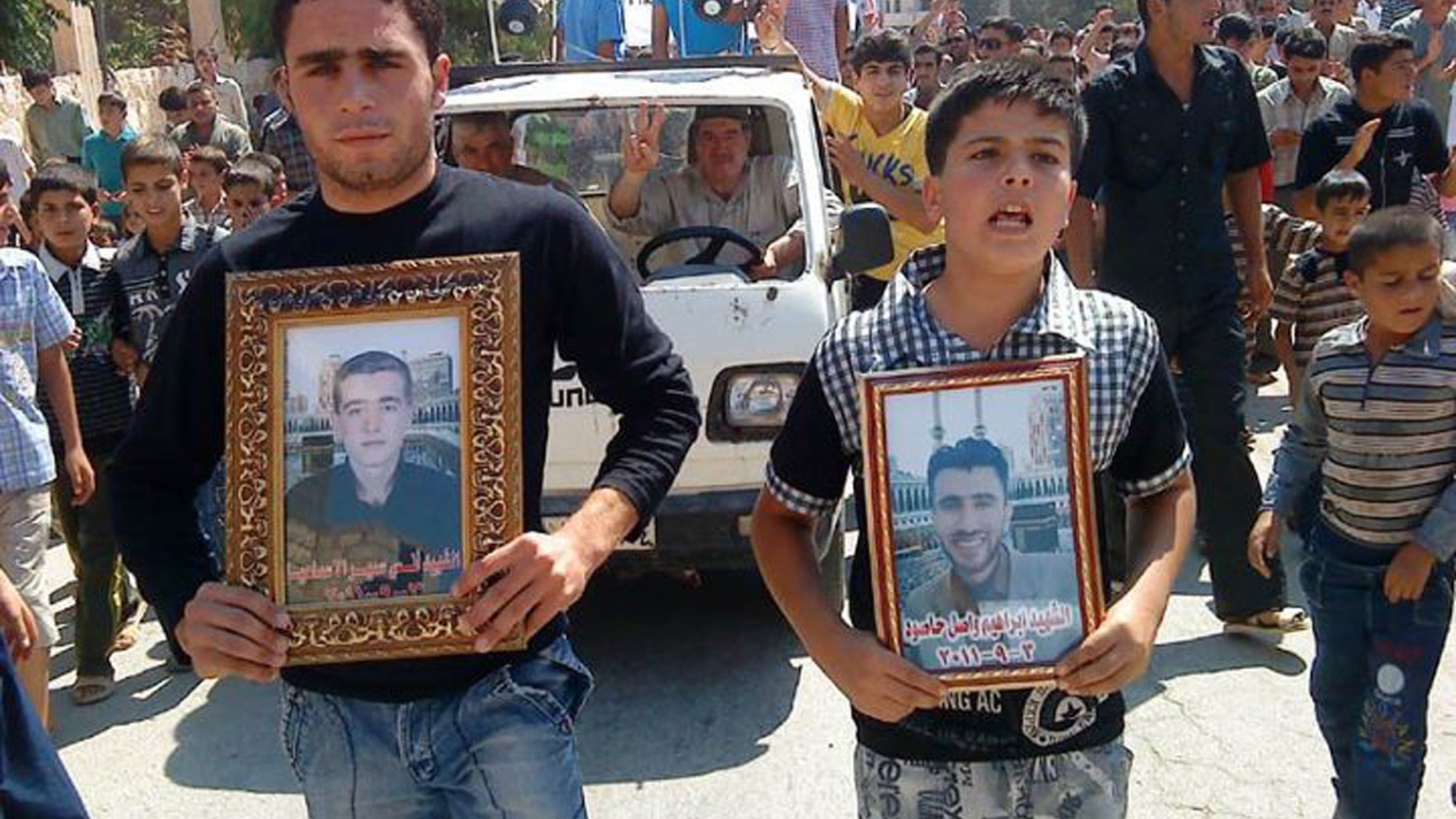 Anti-Syrian President Bashar Assad protesters hold portraits for their dead relatives killed in recent violence, as they march during a demonstration against the Syrian regime, at Maaret Harma village, in Edlib province, Syria, on Friday Sept. 9, 2011.
