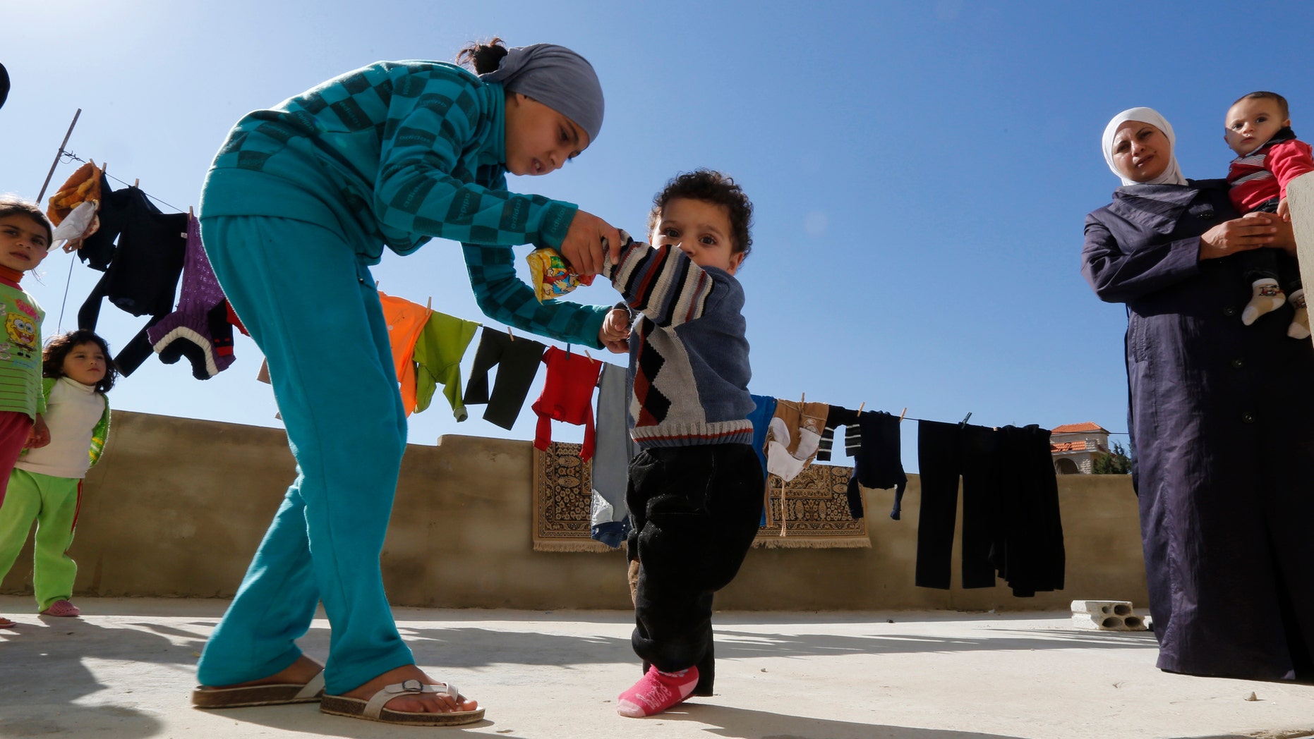 A Syrian refugee girl helps her brother, who the family suspects has polio, to walk as their mother watches in a mosque compound in Shebaa area, southern Lebanon October 28, 2018. (REUTERS/ Jamal Saidi)