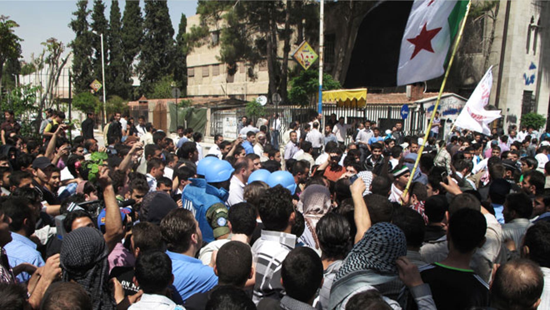 In this Monday, April 23, 2012 photo, Syrian protestors gather around U.N. observers during their visit in Douma near the capital of Damascus, Syria.