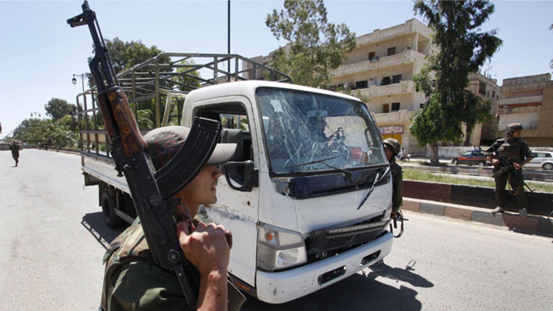 May 9, 2012: A Syrian army soldier secures the scene as he stands next to a military truck which was attacked by a roadside bomb, in Daraa city, southern Syria.