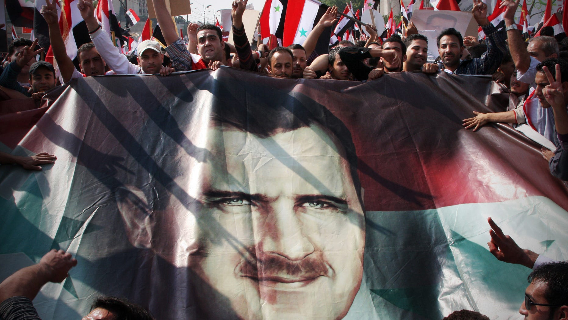 Oct. 26, 2011: Syrian regime supporters flash the V-victory sign as they hold up a portrait of Syrian President Bashar Assad during a rally at Umayyad Square in Damascus, Syria.