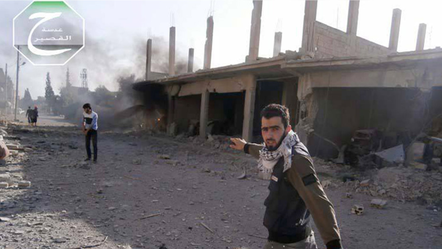 May 31, 2013: This citizen journalism image provided by Qusair Lens, which has been authenticated based on its contents and other AP reporting, shows activist Hadi Abdullah, right, walking on a street hit by the shelling of Hezbolllah Lebanese Shiite group and the Syrian forces loyal to Syrian President Bashar Assad, in the town of Qusair, near the Lebanon border, Homs province, Syria.