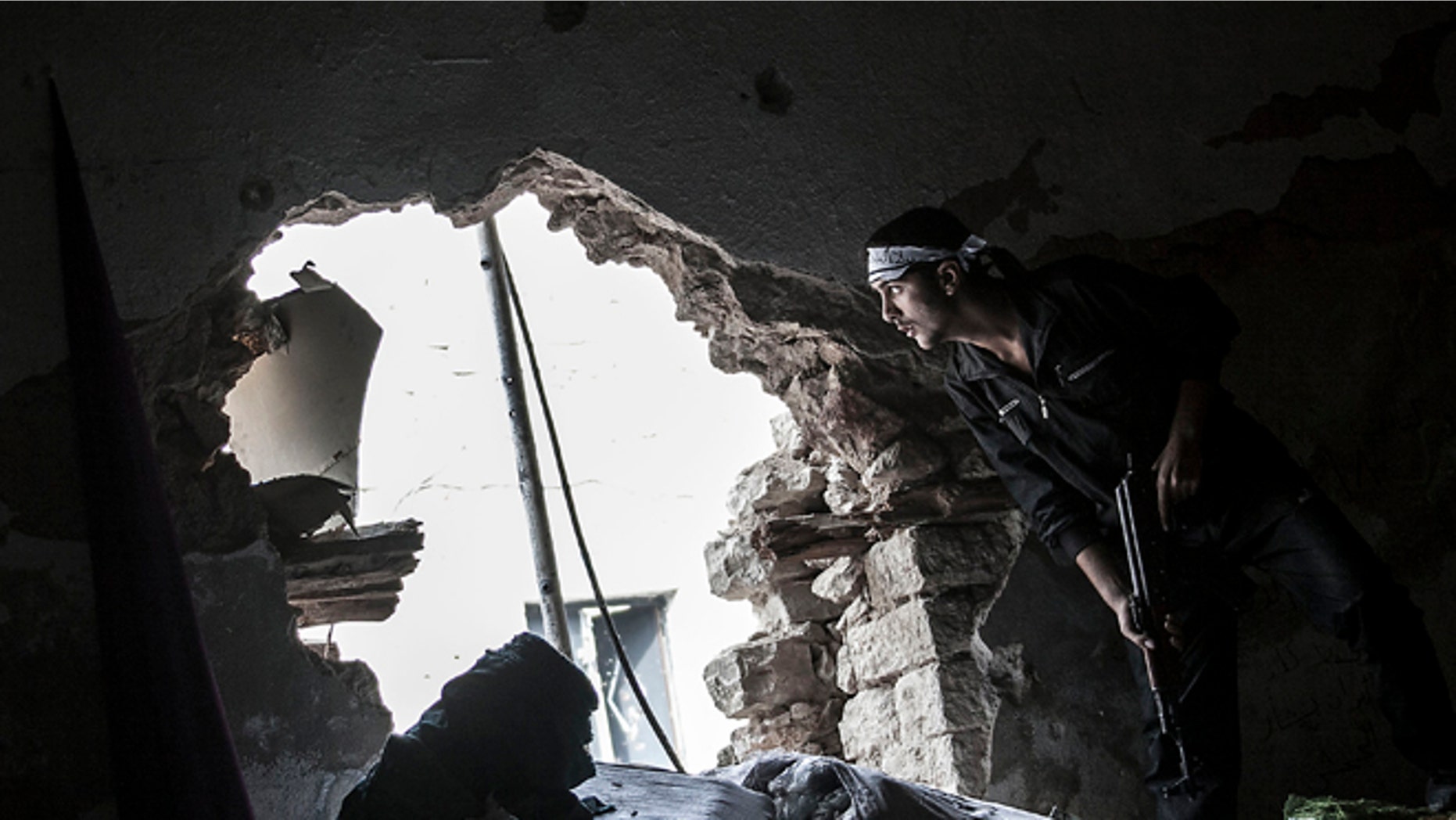 Oct. 24, 2012 photo: A Free Syrian Army fighter watches over an enemy position as rebel fighters belonging to the Liwa Al Tawhid group carry out a military operation at the Moaskar front line, one of the battlefields in the Karmal Jabl neighborhood, in Aleppo, Syria.
