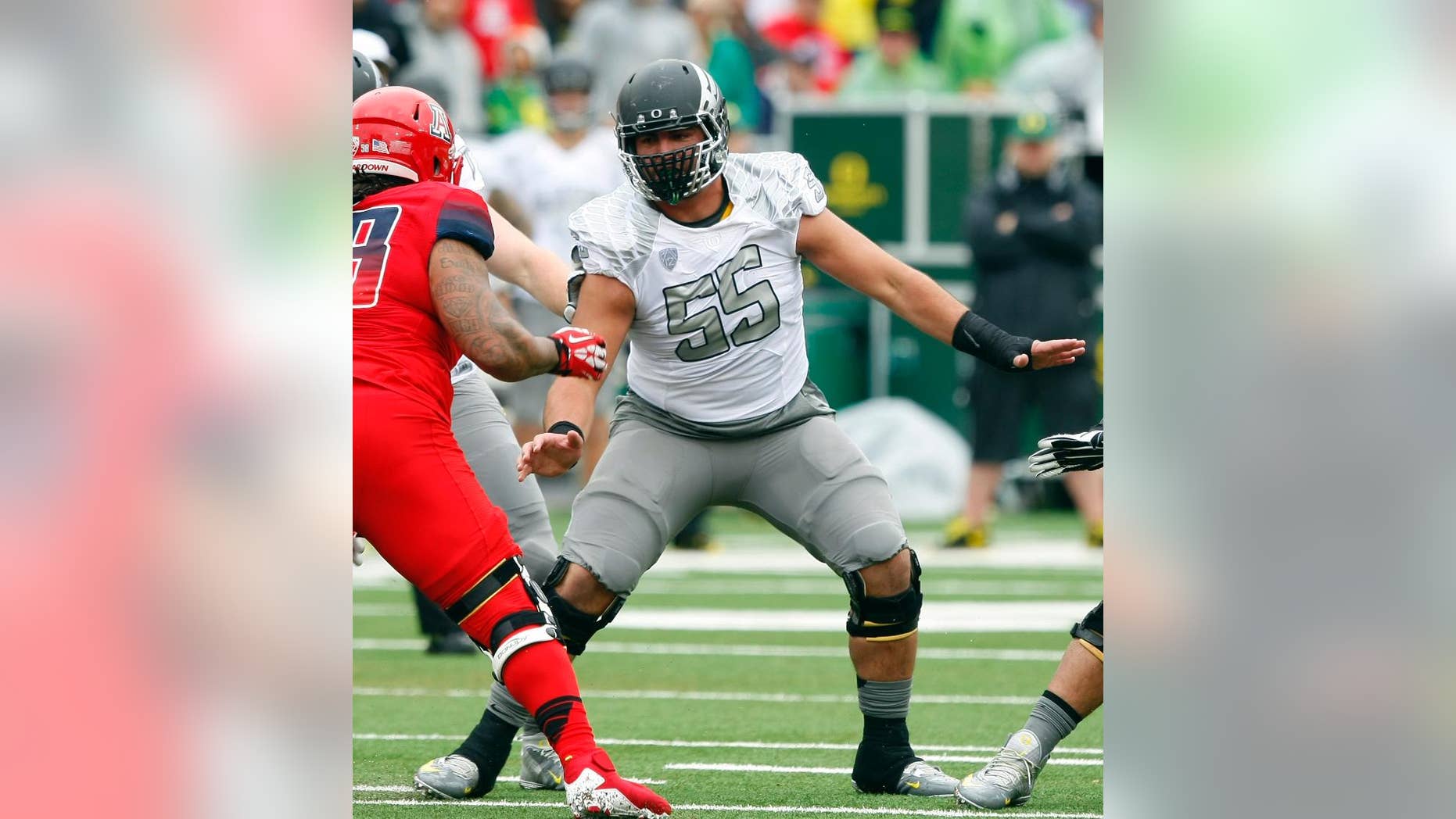 This photo taken Nov. 23, 2013, shows Oregon offensive linesman Hroniss Grasu (55) during the first half of an NCAA football game against Arizona, in Tucson, Ariz. Grasu never would have played football if his parents had their way. Steve and Mariana Grasu, immigrants from Romania, preferred soccer over American football, which that saw as too violent. It was only reluctantly that he was allowed to kick for his high school team, and when a coach put him on the offensive line, well, he didn't exactly mention it to his folks. It was a long, silent ride home when the Grasus attended their son’s first game. "They enjoy it now. They come to every single game, home and away,’’ he laughs.(AP Photo/Rick Scuteri)