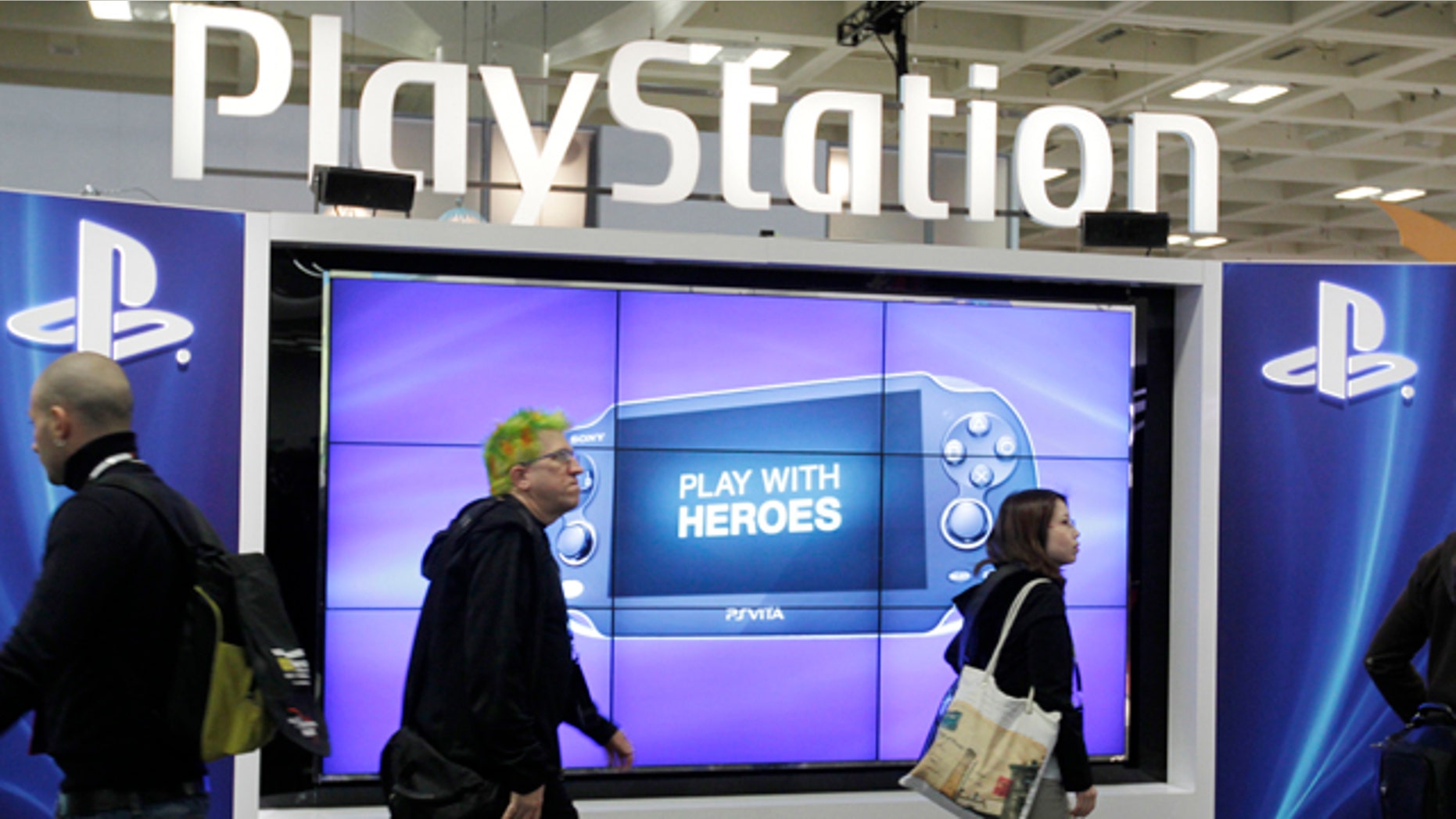FILE- This March 8, 2012 file photo shows attendees walking past the Sony PlayStation PS Vita console on display in the Sony PlayStation booth at the Game Developers Conference in San Francisco. (AP Photo/Paul Sakuma, File)