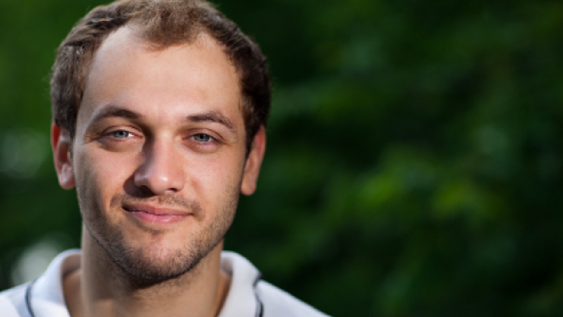 Portrait of a young man on green blurry background - shallow DOF, focus on eyes