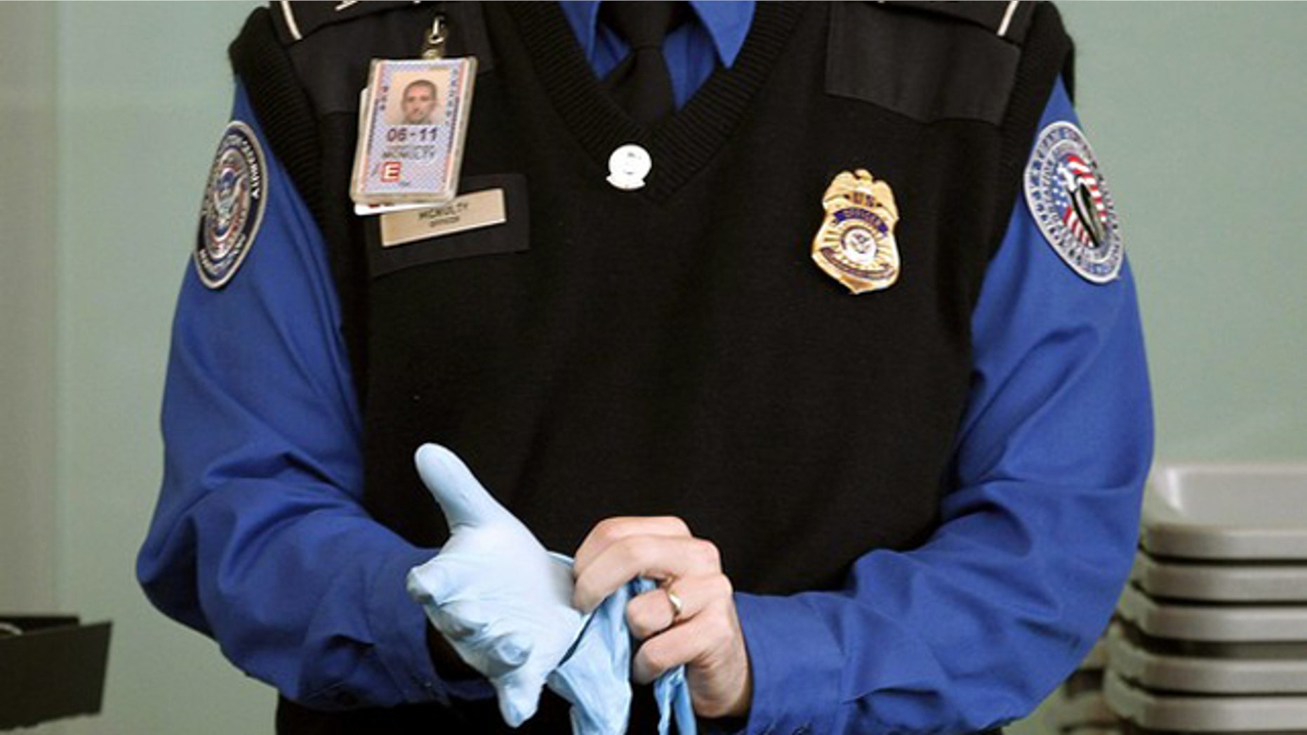 A TSA agent dons rubber gloves at a security checkpoint at Washington Reagan National Airport in Washington, November 22, 2010. U.S. authorities will reconsider airline passenger screening procedures that have caused public uproar on the eve of the busy holiday travel season, the top transport security official said on Monday. REUTERS/Jason Reed (UNITED STATES - Tags: POLITICS TRANSPORT CRIME LAW IMAGES OF THE DAY)