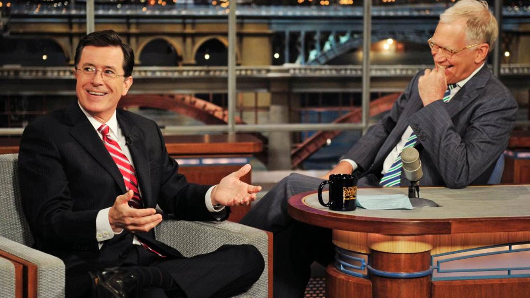 In this May 3, 2012 photo provided by CBS, Stephen Colbert, left, host of the “Colbert Report” on the Comedy Central Network, has a laugh on stage with host David Letterman on the set of the “Late Show with David Letterman,” in New York. Colbert says on a visit to the late-night show he’ll take over next year he’s obviously “thrilled” to be succeeding David Letterman. The Comedy Central host told Letterman on CBS’ “Late Show” on Tuesday, April 22, 2014, he’s going to do whatever Letterman has done. (AP Photo/CBS, John Paul Filo) MANDATORY CREDIT, NO SALES, NO ARCHIVE, FOR NORTH AMERICAN USE ONLY