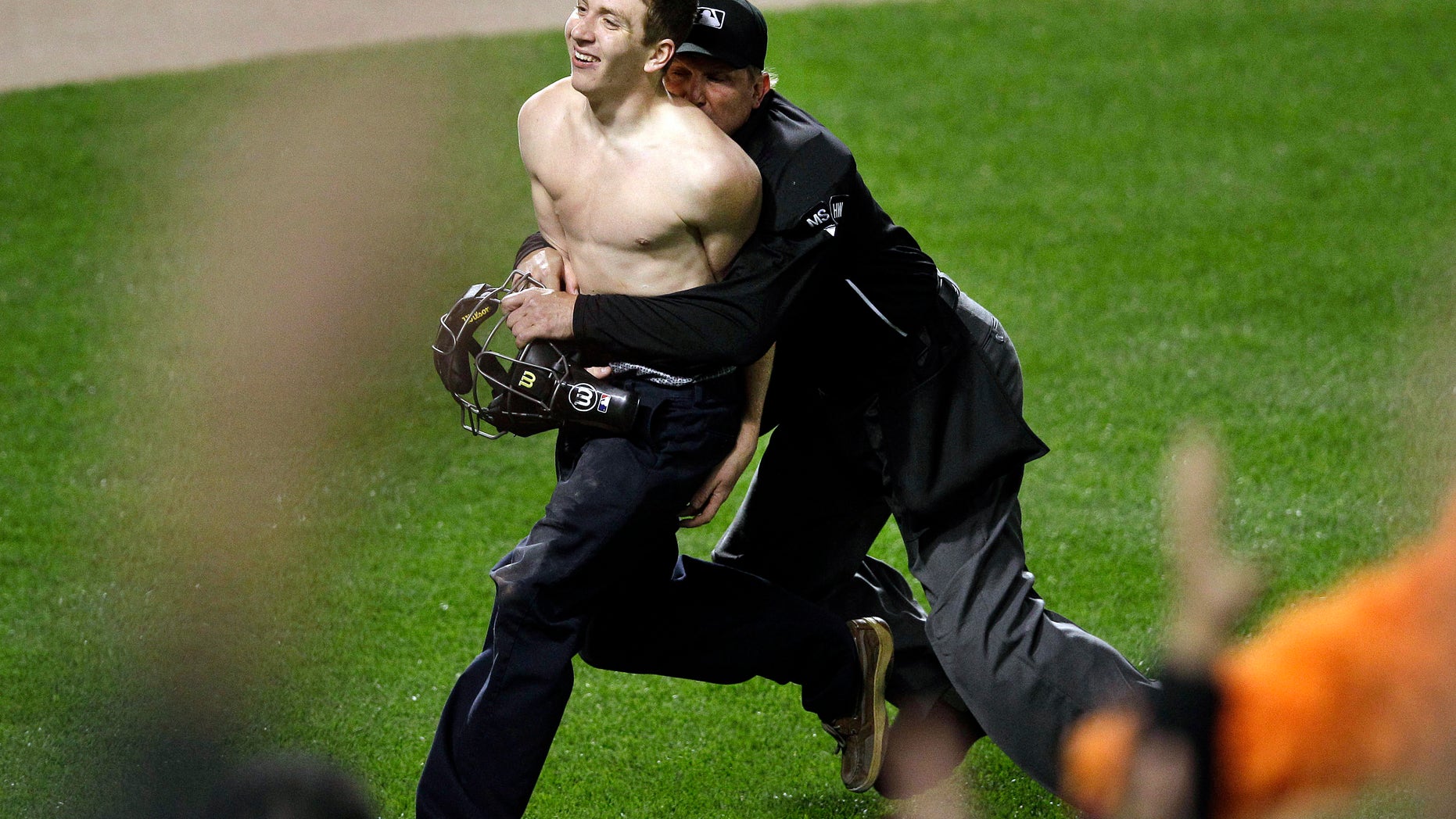 Umpire Jeff Kellogg, right, tackles a fan who ran onto the field in the middle of the seventh inning of a baseball game between the Oakland Athletics and the Baltimore Orioles in Baltimore, Friday, April 27, 2012. (AP Photo/Patrick Semansky)