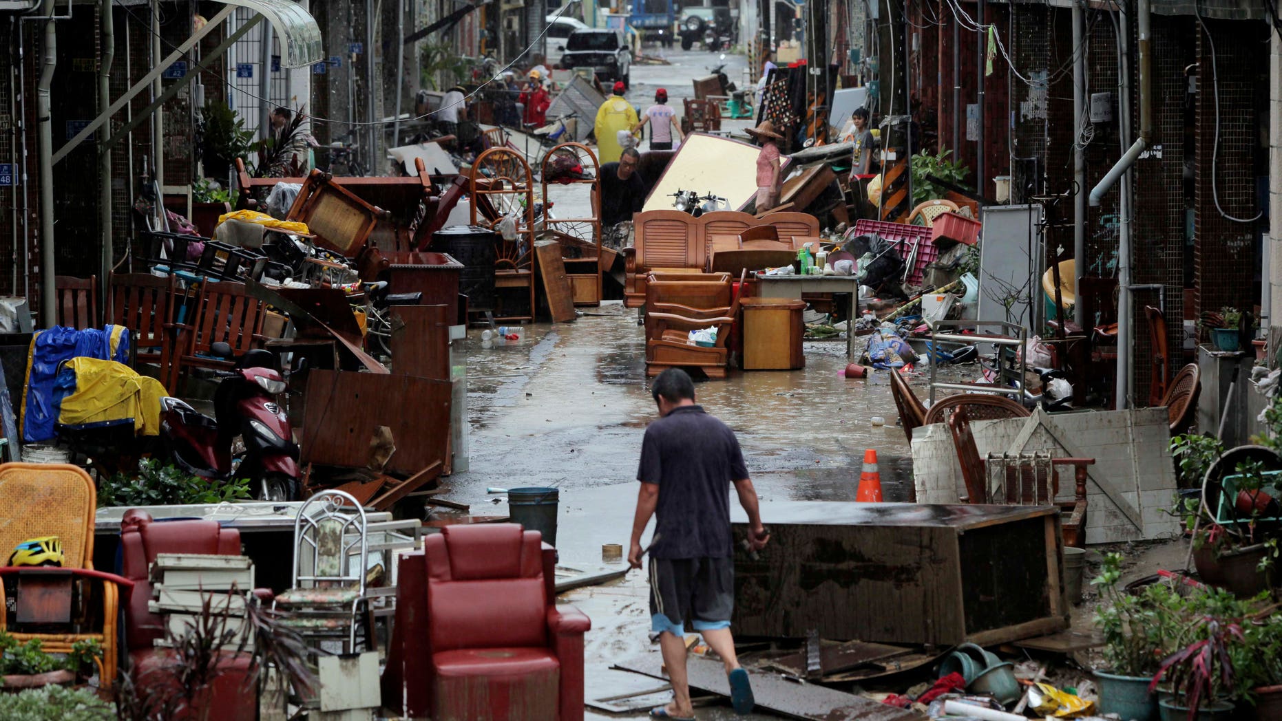 A man walks down a lane of water damaged furniture from heavy rains brought by Typhoon Tembin in Pingtung county, Taiwan, Friday, Aug. 24, 2012. The typhoon crossed over southern Taiwan on Friday morning, causing flooding and wind damage but largely sparing the island's heavily populated areas. (AP Photo) TAIWAN OUT