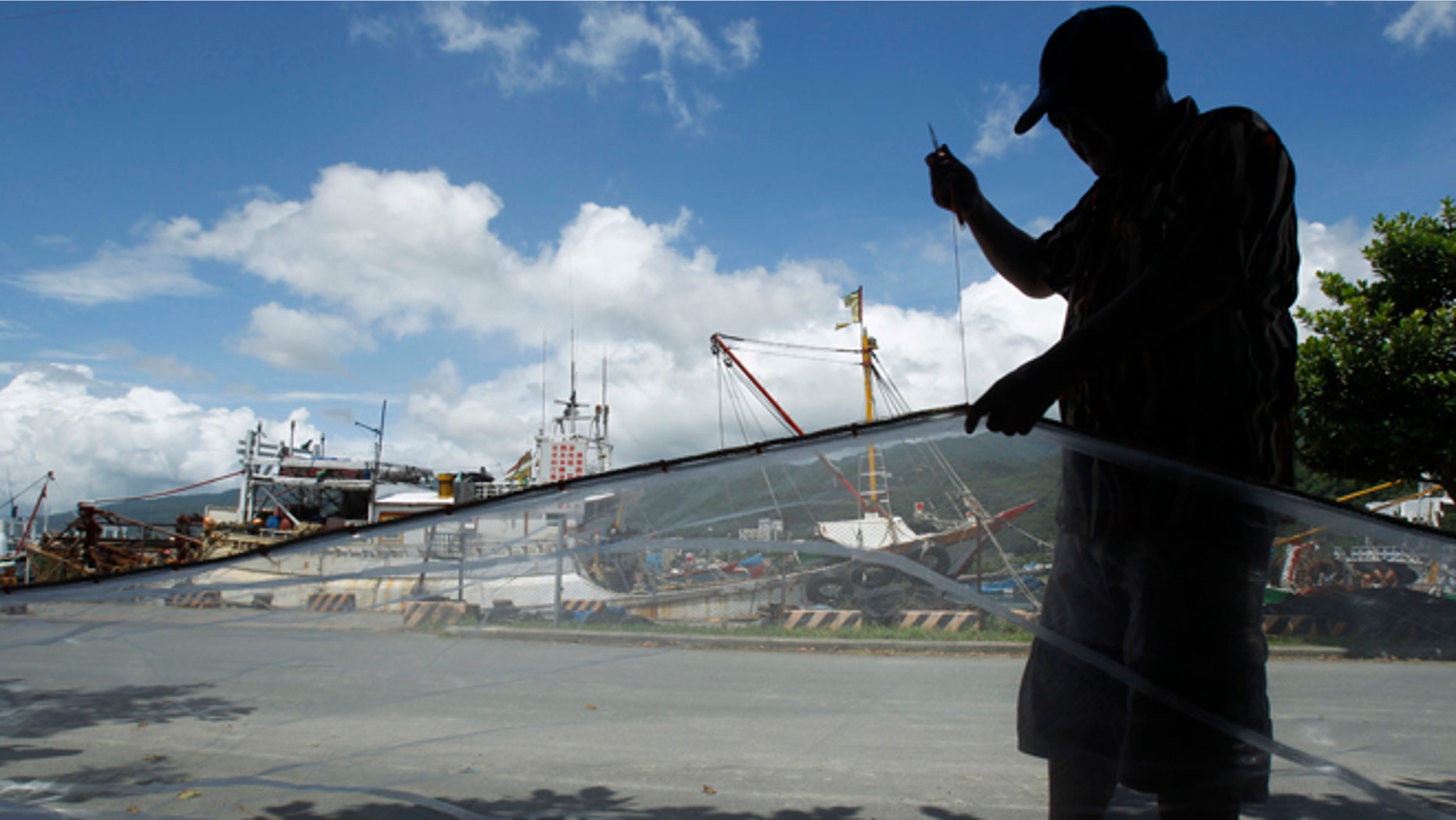 August 23, 2012: A fisherman repairs his nets at the dock as he waits out approaching Typhoon Tembin in the coastal village of Ilan, Taiwan.