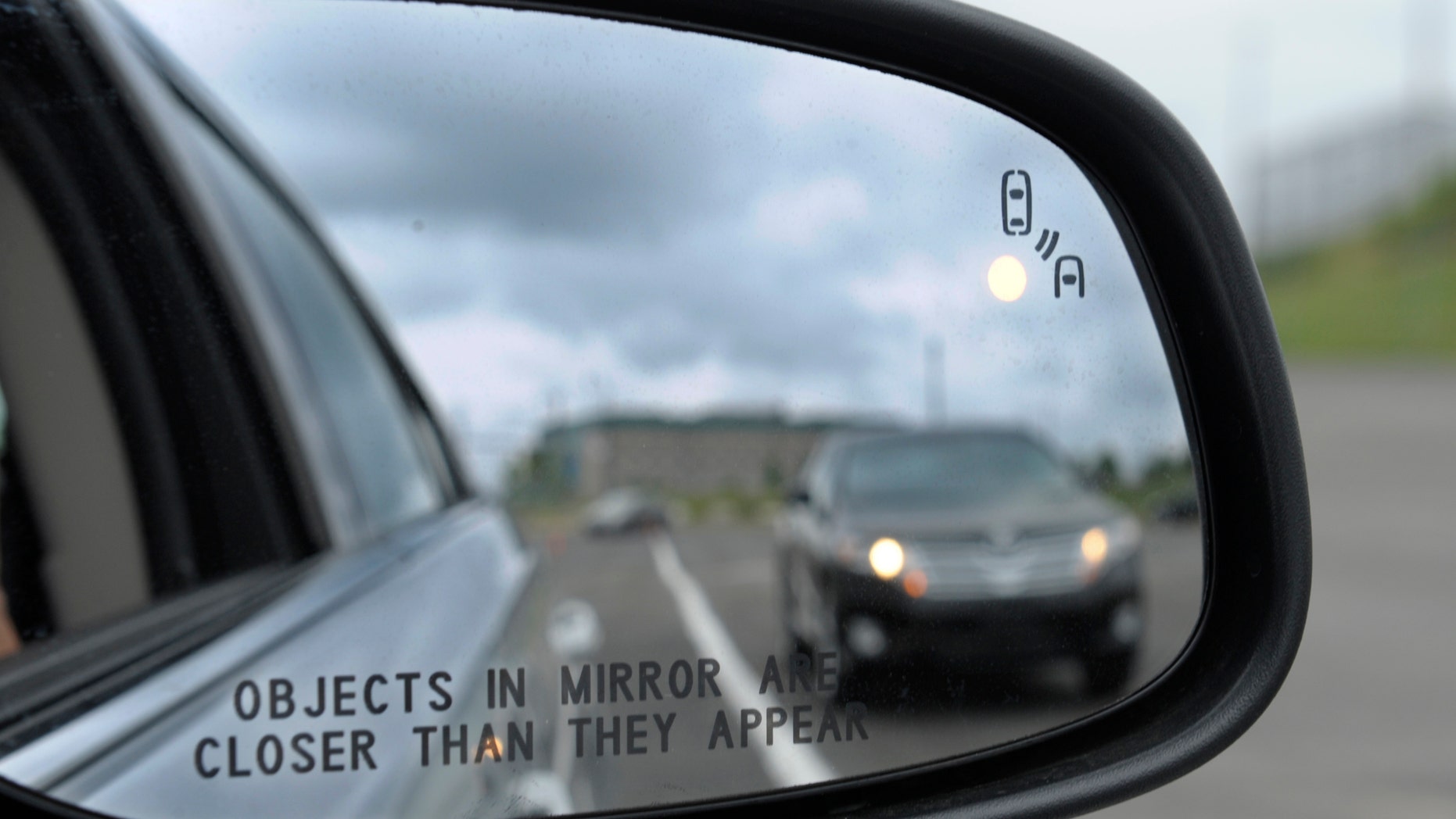 This May 22, 2012 file photo shows a side mirror warning signal in a Ford Taurus at an automobile testing area in Oxon Hill, Md. Federal officials are planning to announce Monday whether automakers should be required to equip new cars and light trucks with technology that enables vehicles to communicate with each other to prevent collisions. Such vehicle-to-vehicle communication could eventually transform traffic safety.