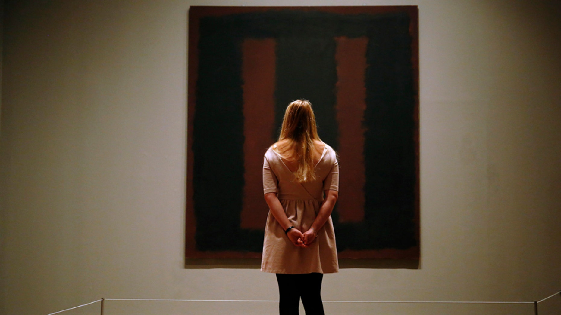A member of Tate staff poses with the restored Mark Rothko artwork "Black on Maroon, 1958" at the Tate Modern in London May 13, 2014. The picture was vandalised in 2012 by Polish man Wlodzimierz Umaniec - known also as Vladimir Umanets - who wrote "Vladimir Umanets '12 A potential piece of yellowism" on the canvas. He has since been given a jail sentence for the action. REUTERS/Luke MacGregor (BRITAIN - Tags: CRIME LAW SOCIETY TPX IMAGES OF THE DAY) - RTR3OWAI