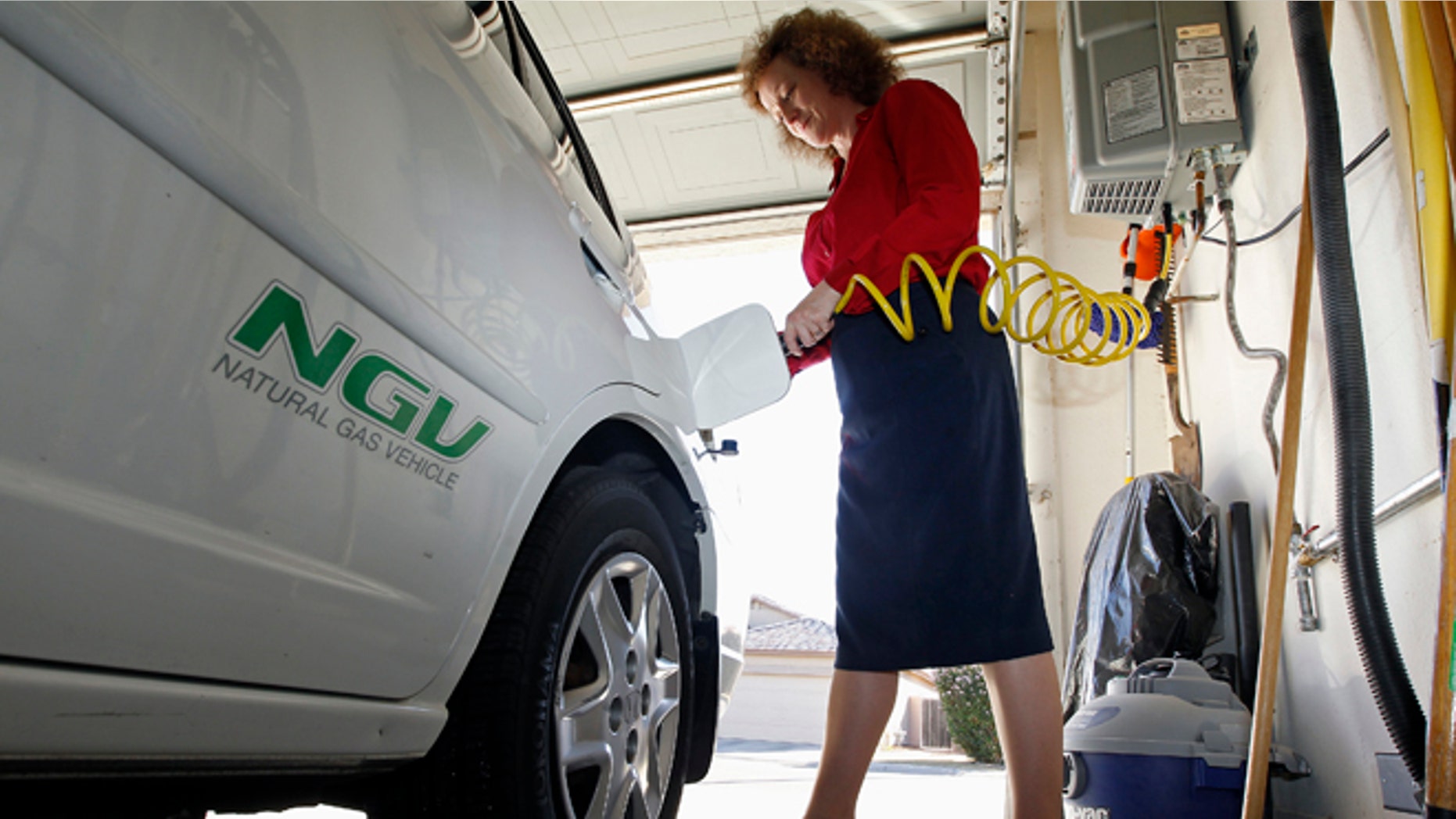 FILE: October 3, 2013. A woman connects the nozzle of a home refueling station to her 2003 natural gas powered Honda Civic, Chandler, Ariz.