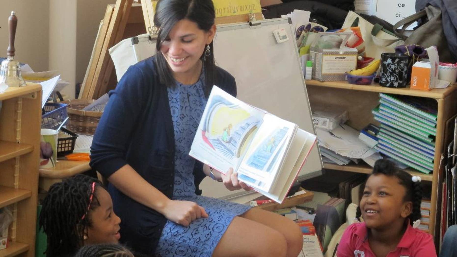 FILE - In this April 10, 2014 file photo, student teacher Franchesca Moreno, 21, reads to Andreanna Thomas, 6, right, and Alana Cawthon, upper left, at Bennett Park Montessori School in Buffalo, N.Y. Moreno is among the first future New York teachers required to pass a kind of "bar exam" to become professionally certified. (AP Photo)