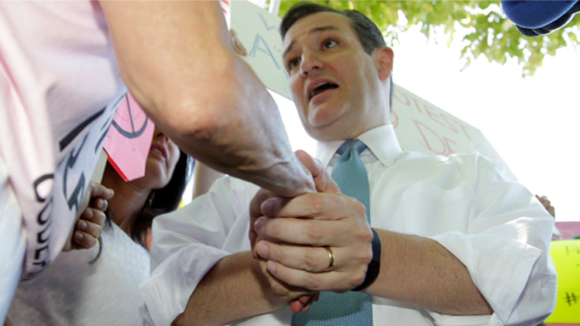 Republican Presidential candidate, Sen. Ted Cruz, R-Texas, shakes hands with Code Pink anti-war group co-founder Medea Benjamin, left, after being interrupted by Benjamin during a demonstration by the Concerned Women for America Legislative Action Committee (CWALAC) to address the Obama administration's nuclear deal with Iran and the fact it leaves four Americans behind, Thursday, July 23, 2015, near the White House in Washington. (AP Photo/Luis M. Alvarez)