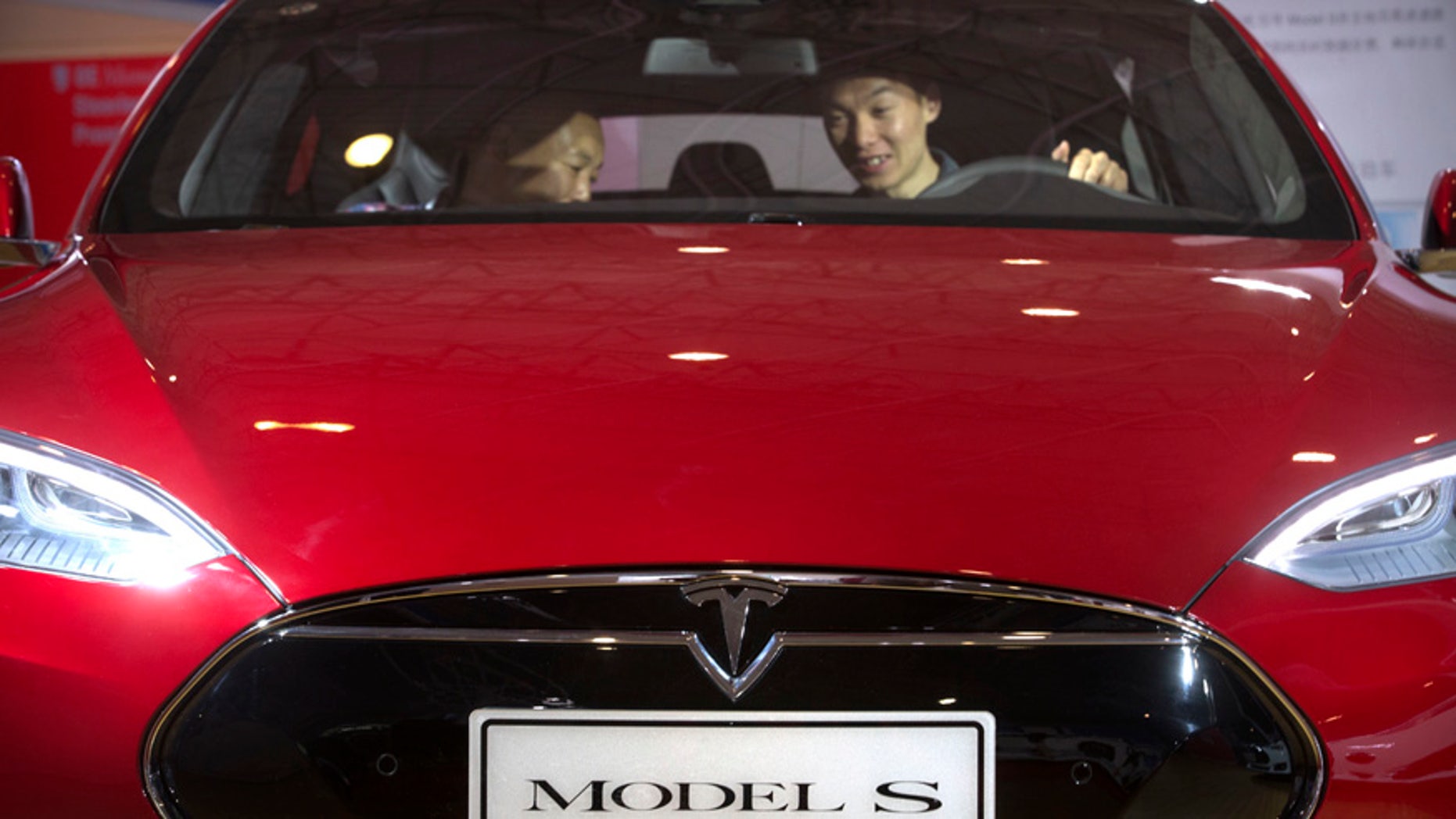 FILE - In this Monday, April 25, 2016, file photo, a man sits behind the steering wheel of a Tesla Model S electric car on display at the Beijing International Automotive Exhibition in Beijing. Tesla said Thursday, June 9, 2016, that it has started selling a cheaper version of its Model S car in an attempt to make its electric vehicles more affordable for more people. The new version, called the Model S 60, starts at $66,000. An all-wheel drive version of the Model S 60 will start at $71,000. Both cost less that the current Model S 90D, which starts at $89,500. (AP Photo/Mark Schiefelbein, File)